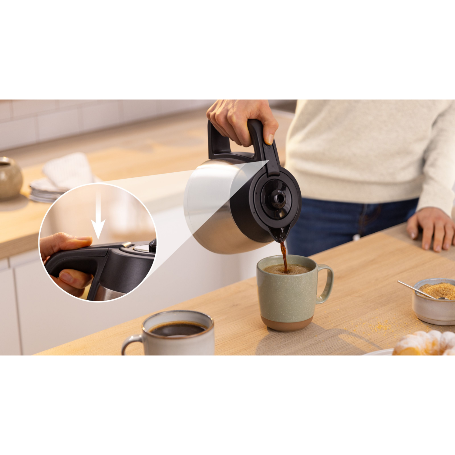 Een persoon schenkt koffie uit een thermoskan in een mok. Een close-up toont de knop van de kan die wordt ingedrukt.