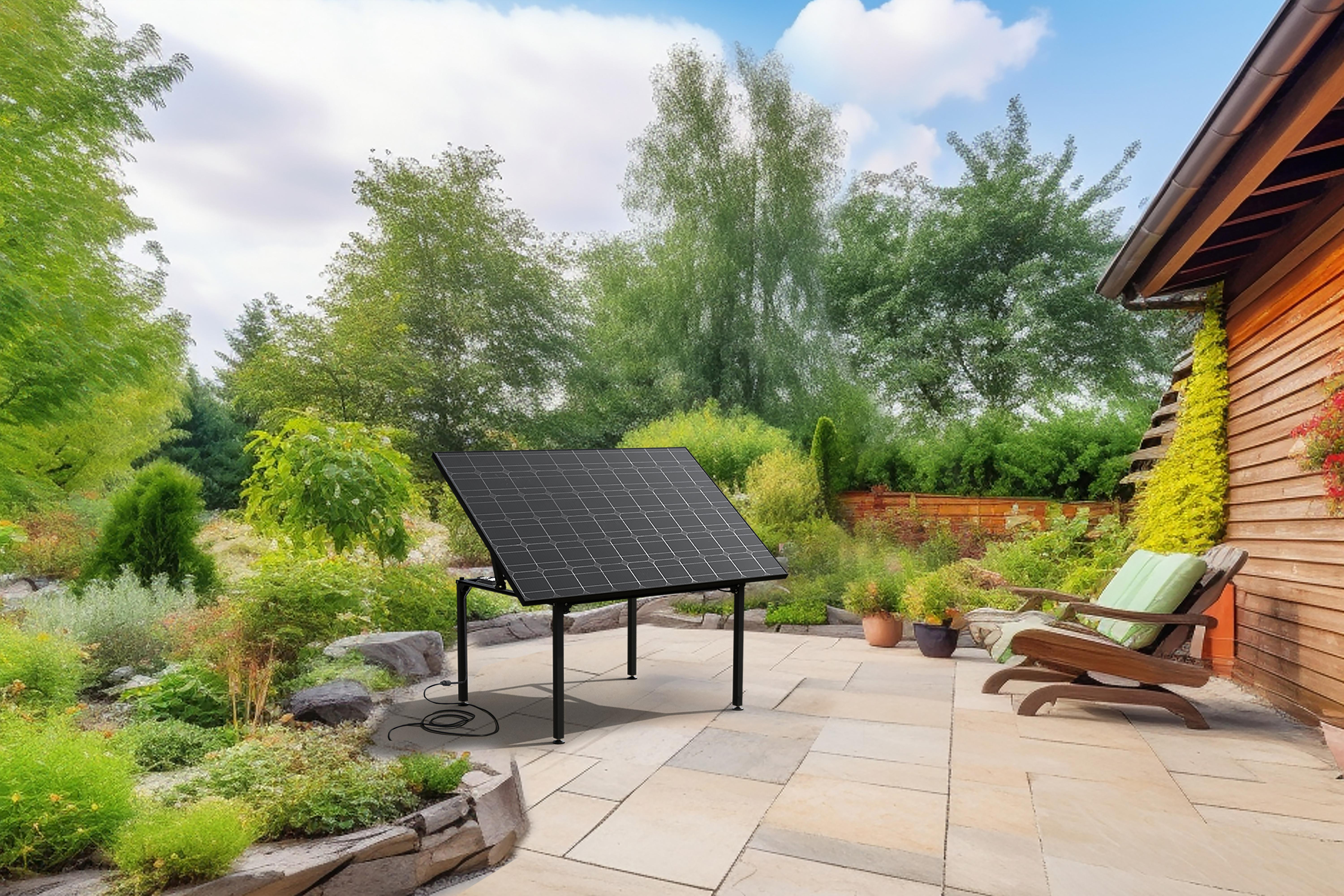 Ein Solarpanel auf einer Terrasse, Bäume im Hintergrund und ein Holzhaus. Ein sonniger Tag.