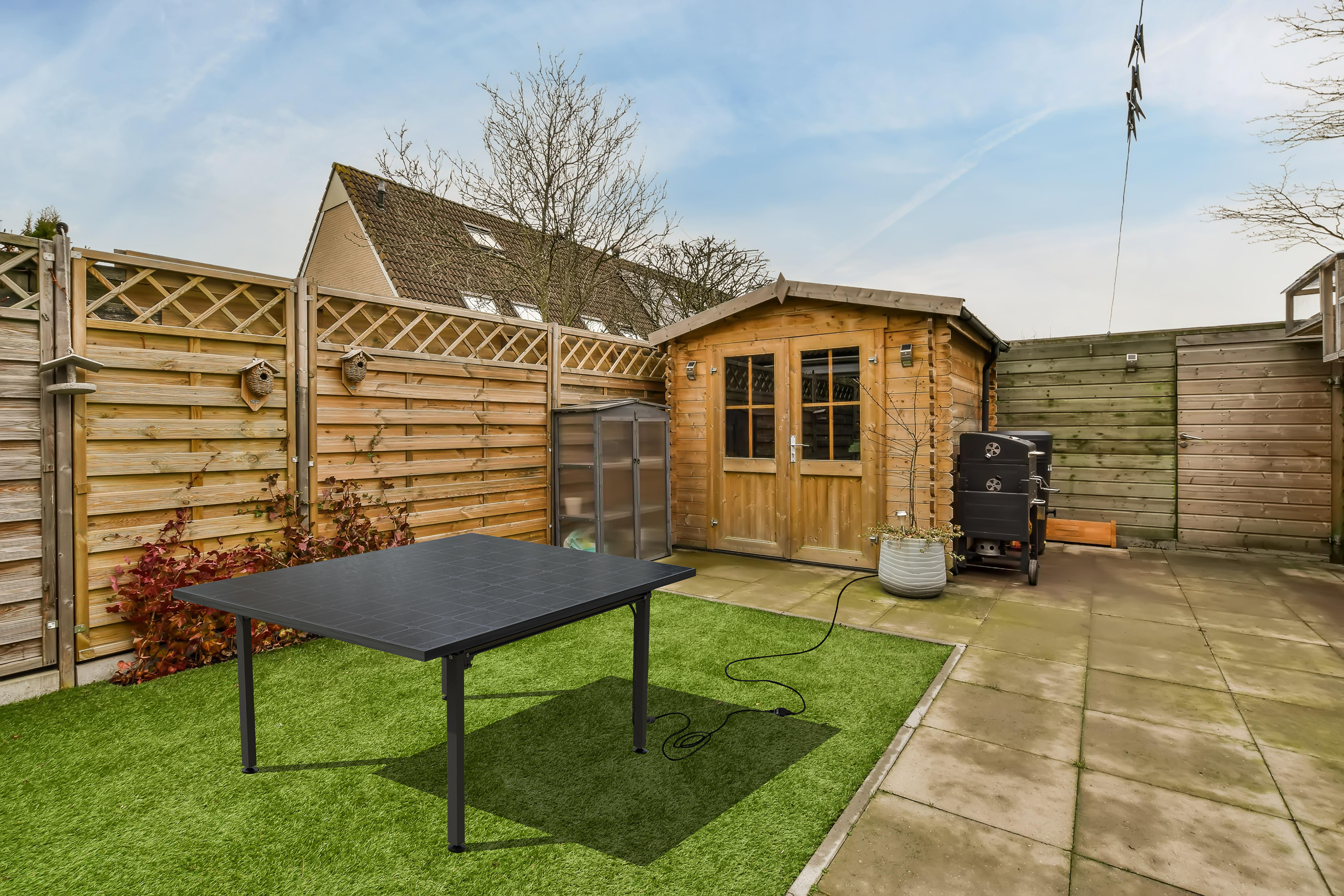 Hinterhof mit grünem Gras, Holzschuppen und Zaun.