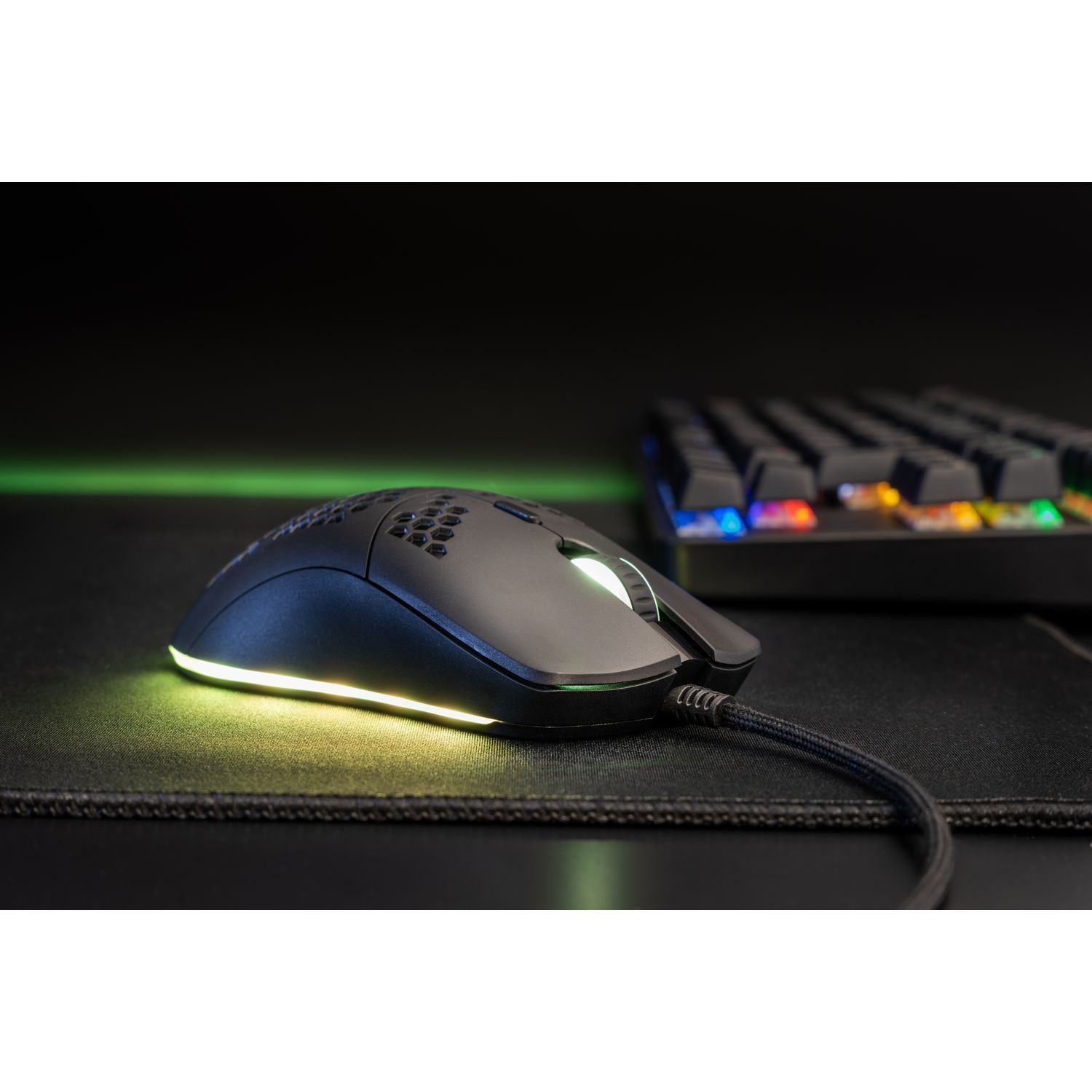 A black computer mouse with a light on it and a keyboard in the background.