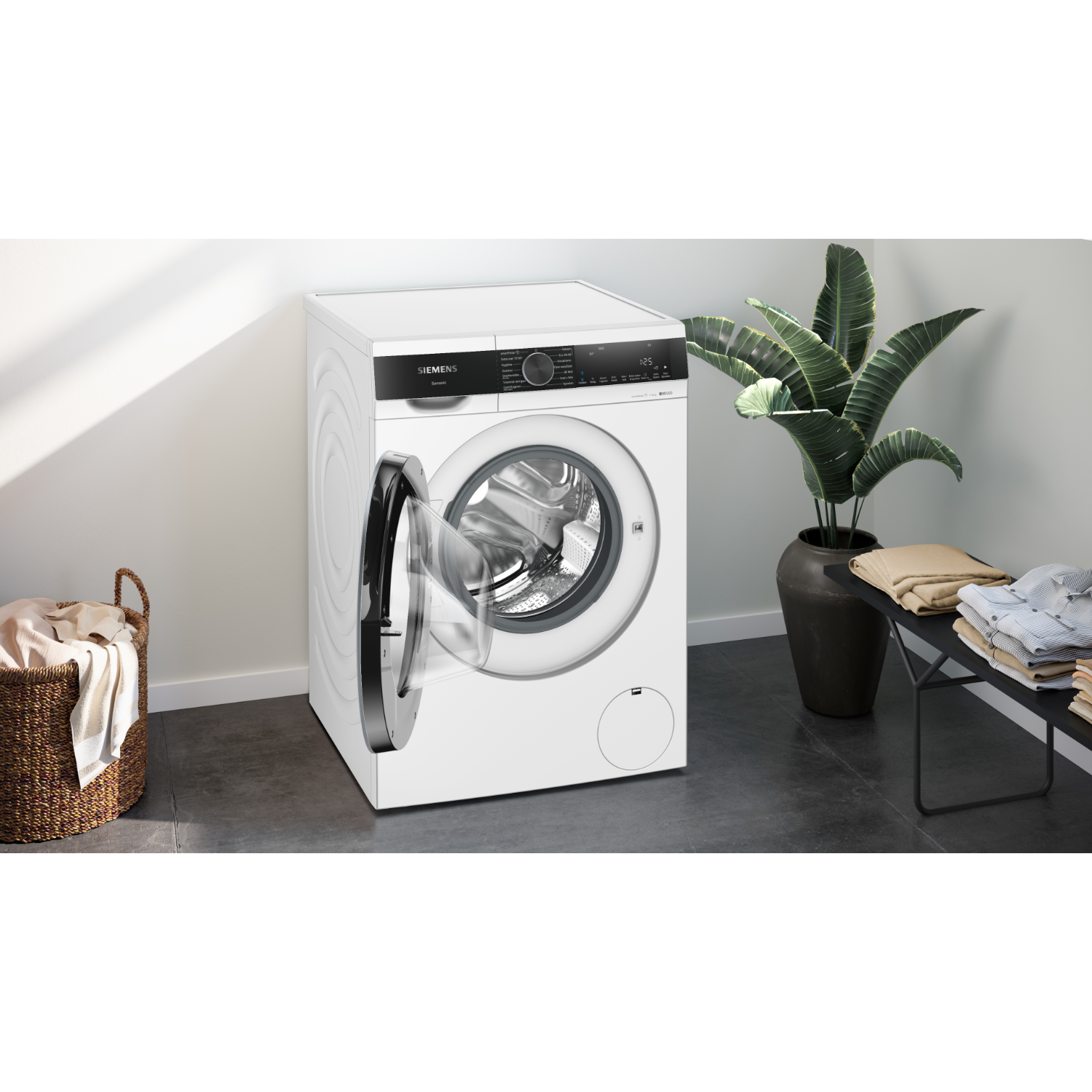 White Siemens washing machine with open door. A laundry basket and plant are in the scene.