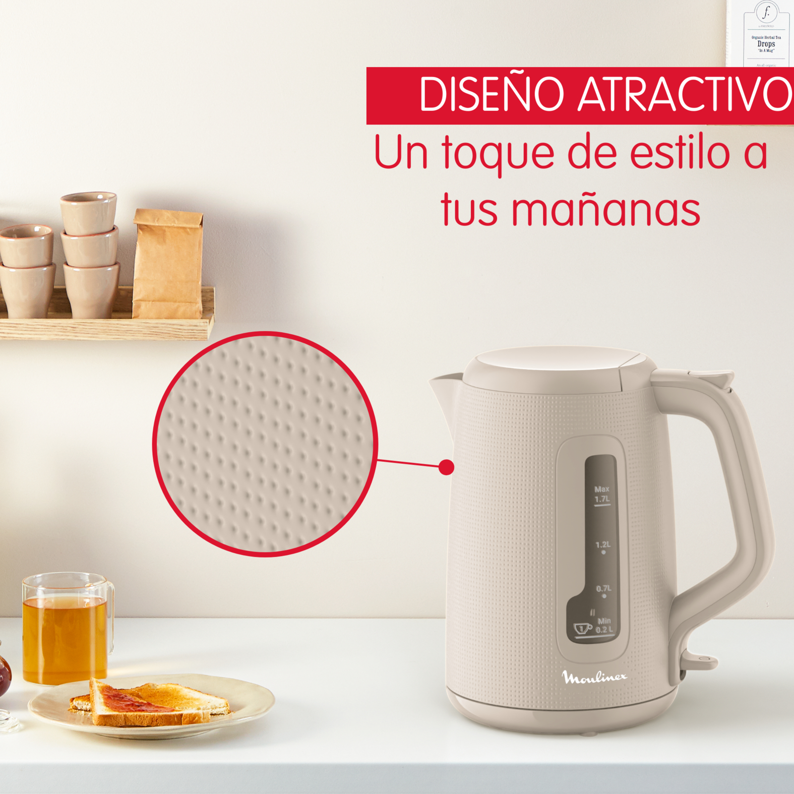 Hervidor beige sobre superficie blanca, tostada y vaso de zumo a la izquierda.