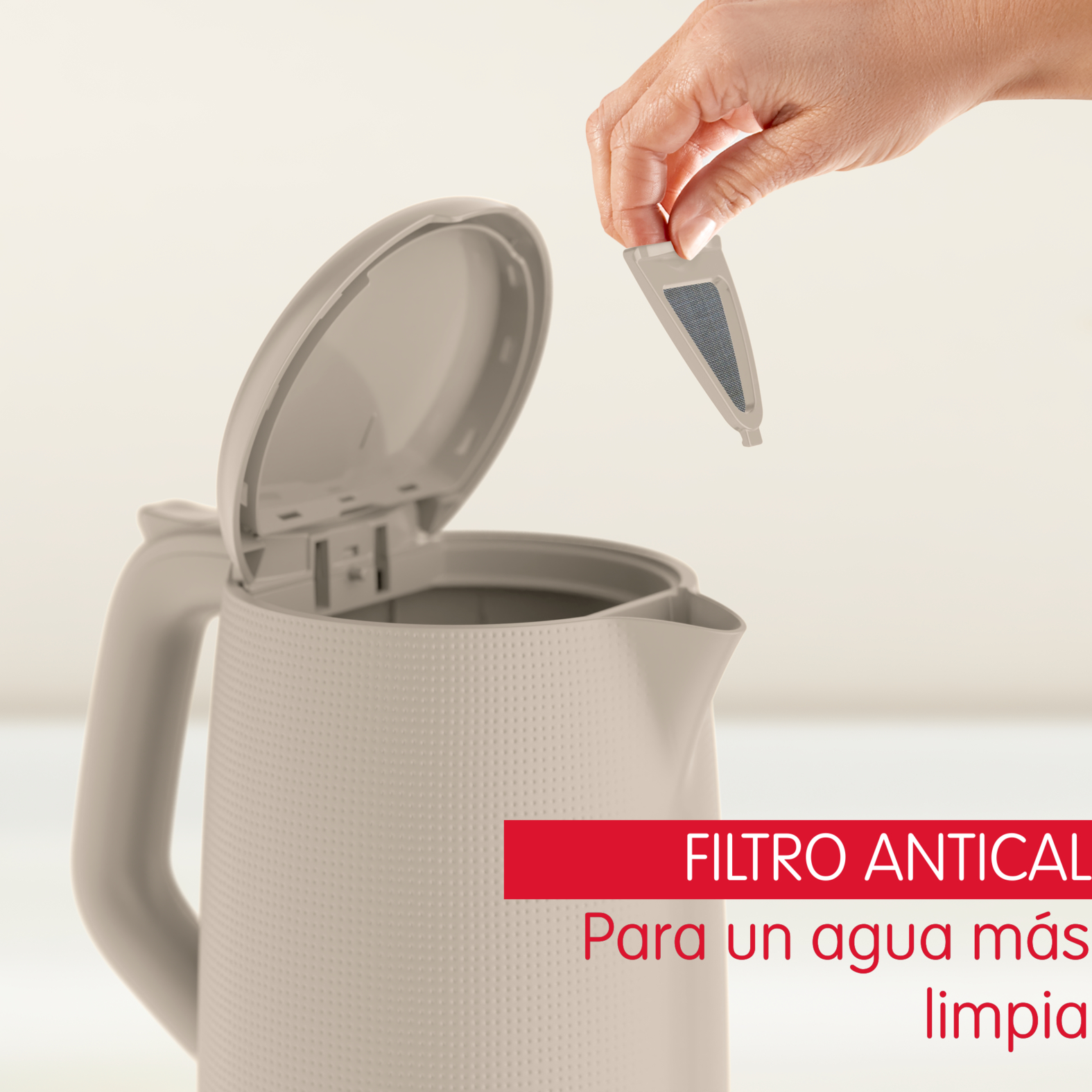 Mano sosteniendo filtro, cerca de una tetera beige.