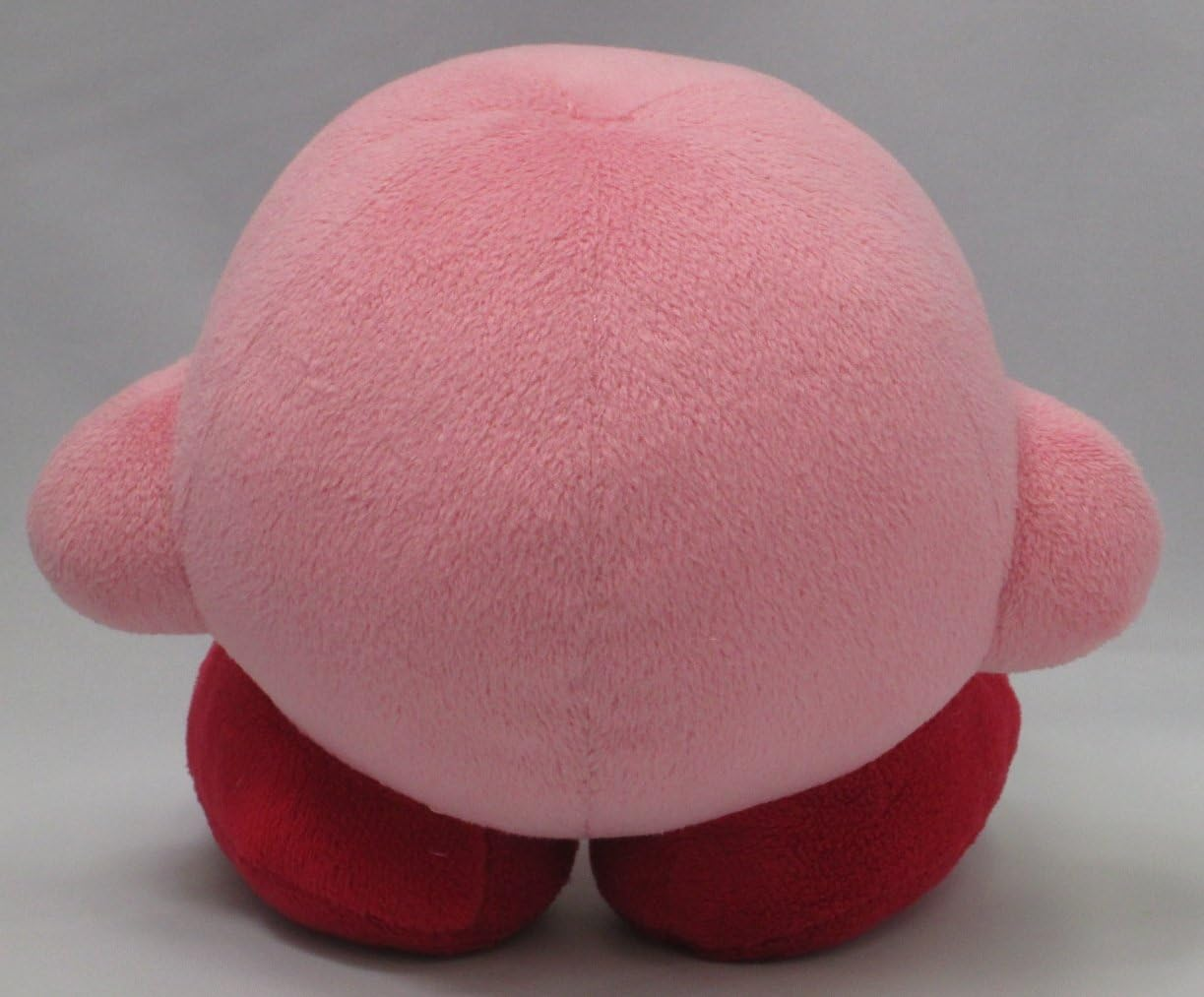 Rosa Plüsch-Kirby-Spielzeug mit roten Füßen, von hinten gesehen.