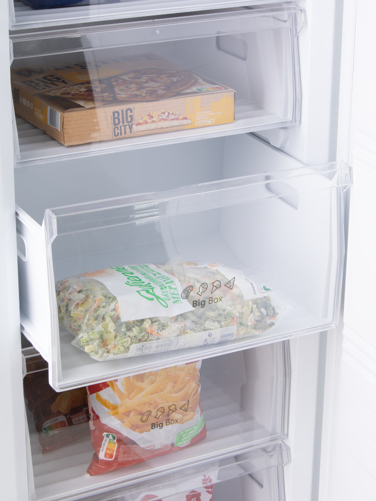 Intérieur du réfrigérateur avec tiroirs. Aliments surgelés : pizza, légumes et frites.