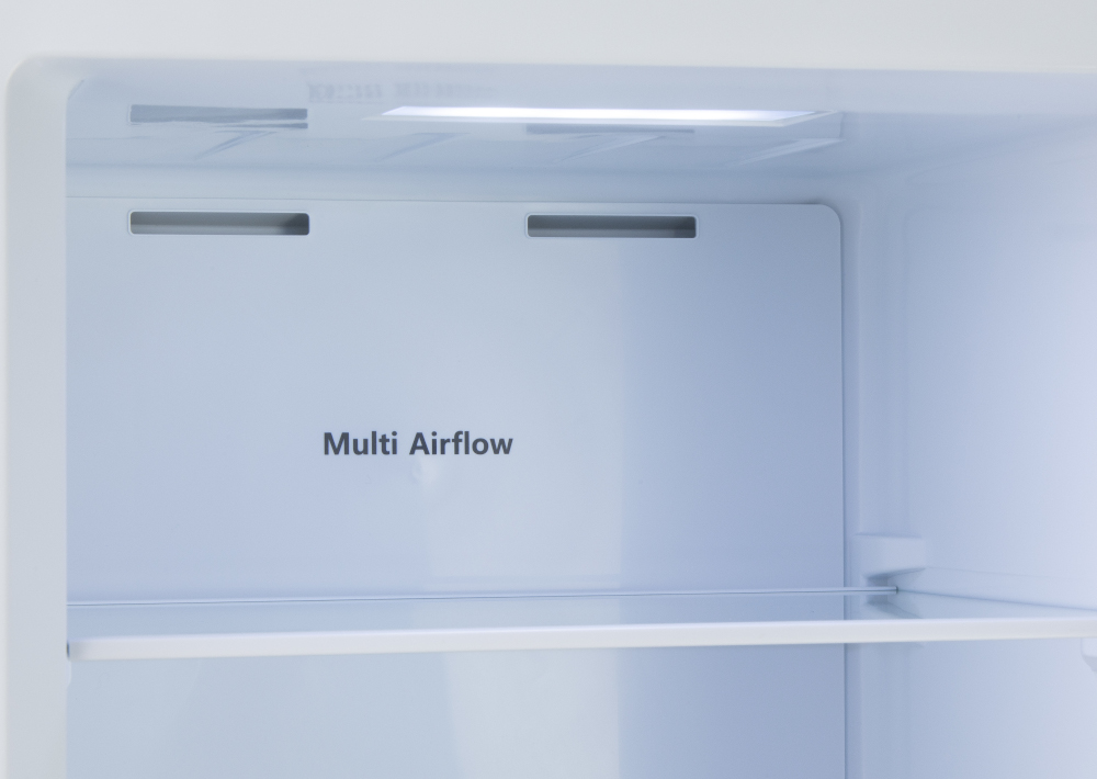 Intérieur de réfrigérateur blanc avec texte 'Multi Airflow' sur le panneau arrière et une étagère en verre.