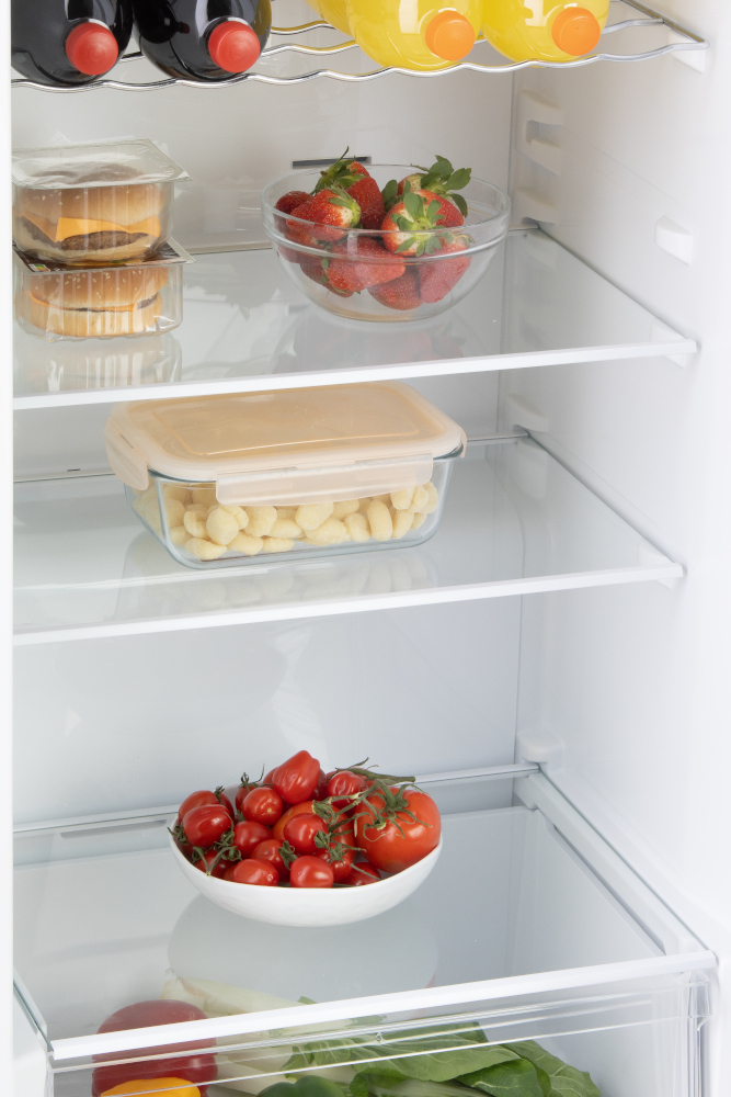 Refrigerator interior with shelves. Strawberries, tomatoes, and other food items.