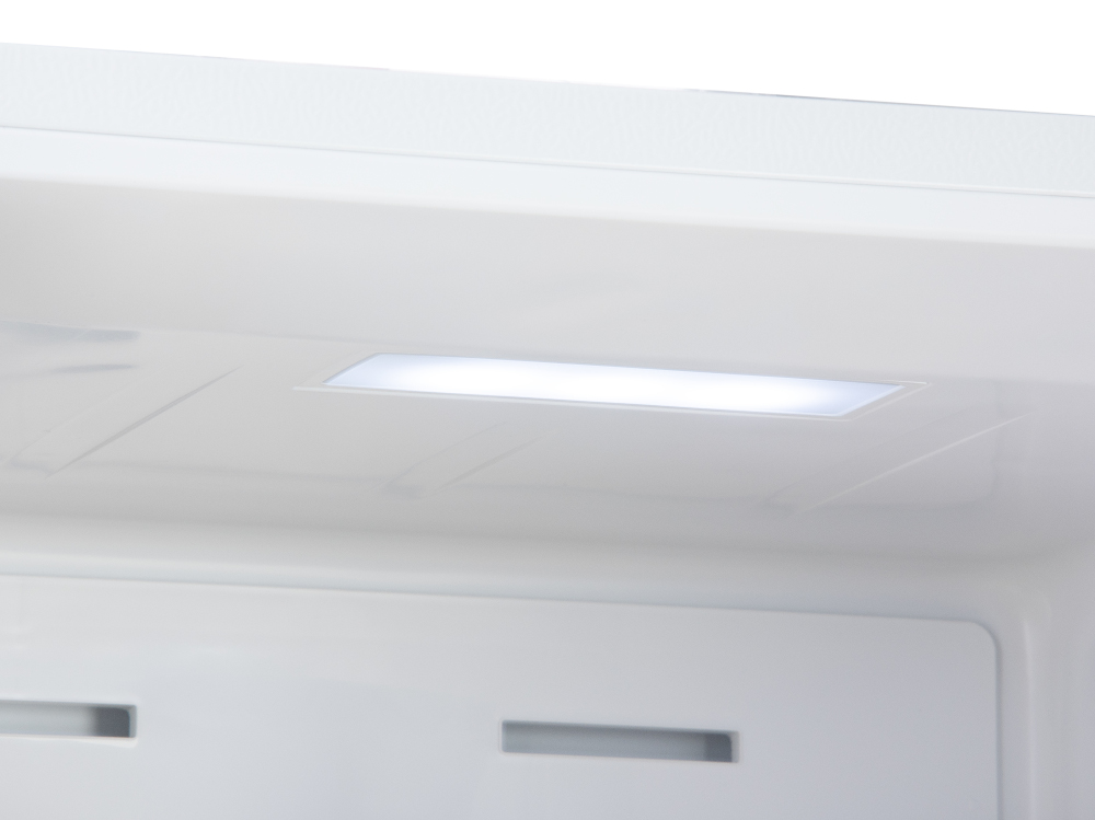 Inside view of a white fridge. A bright light shines from a rectangular fixture on the ceiling.