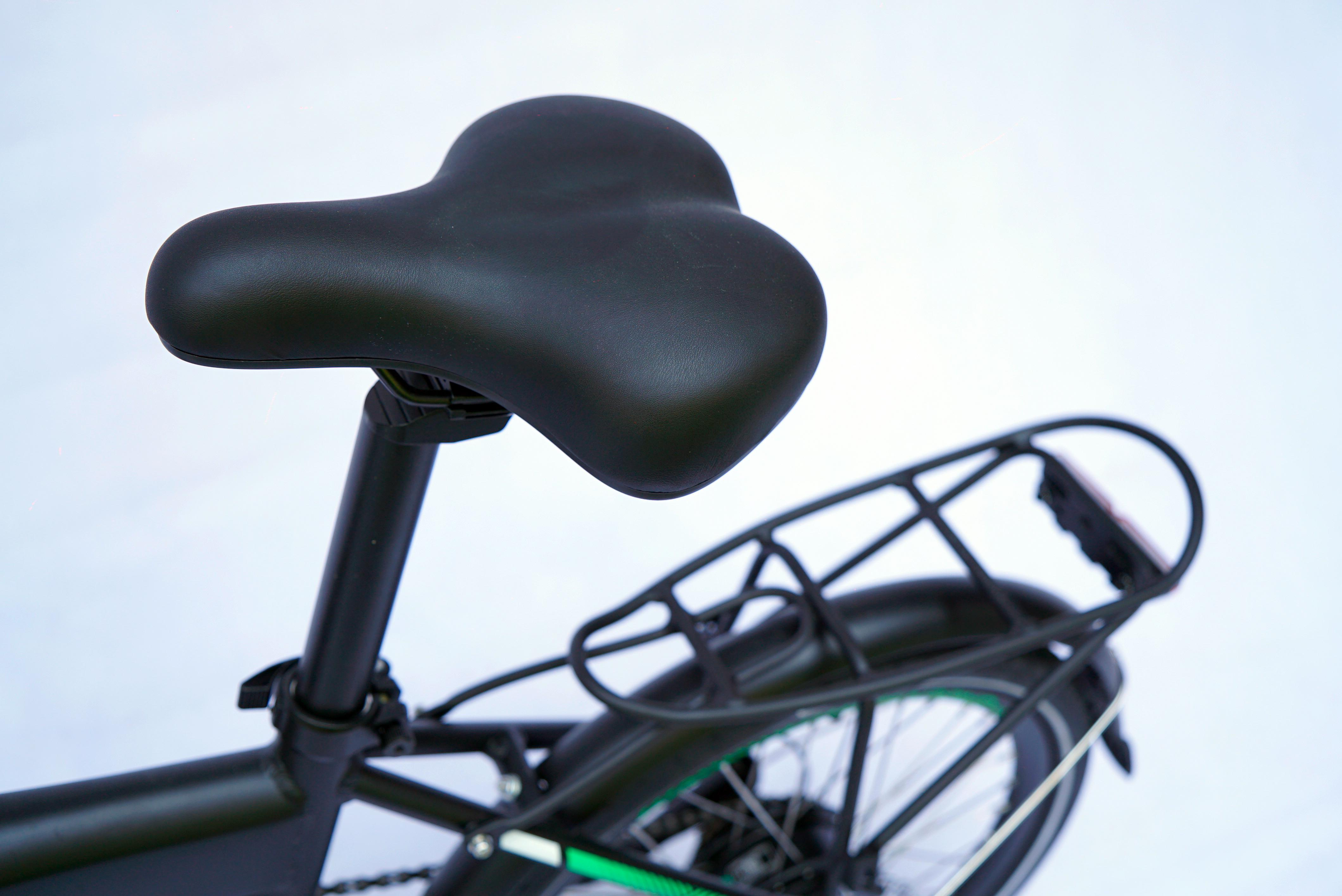 Ein schwarzer Fahrradsattel und Gepäckträger an einem Fahrrad. Der Sattel ist gebogen.