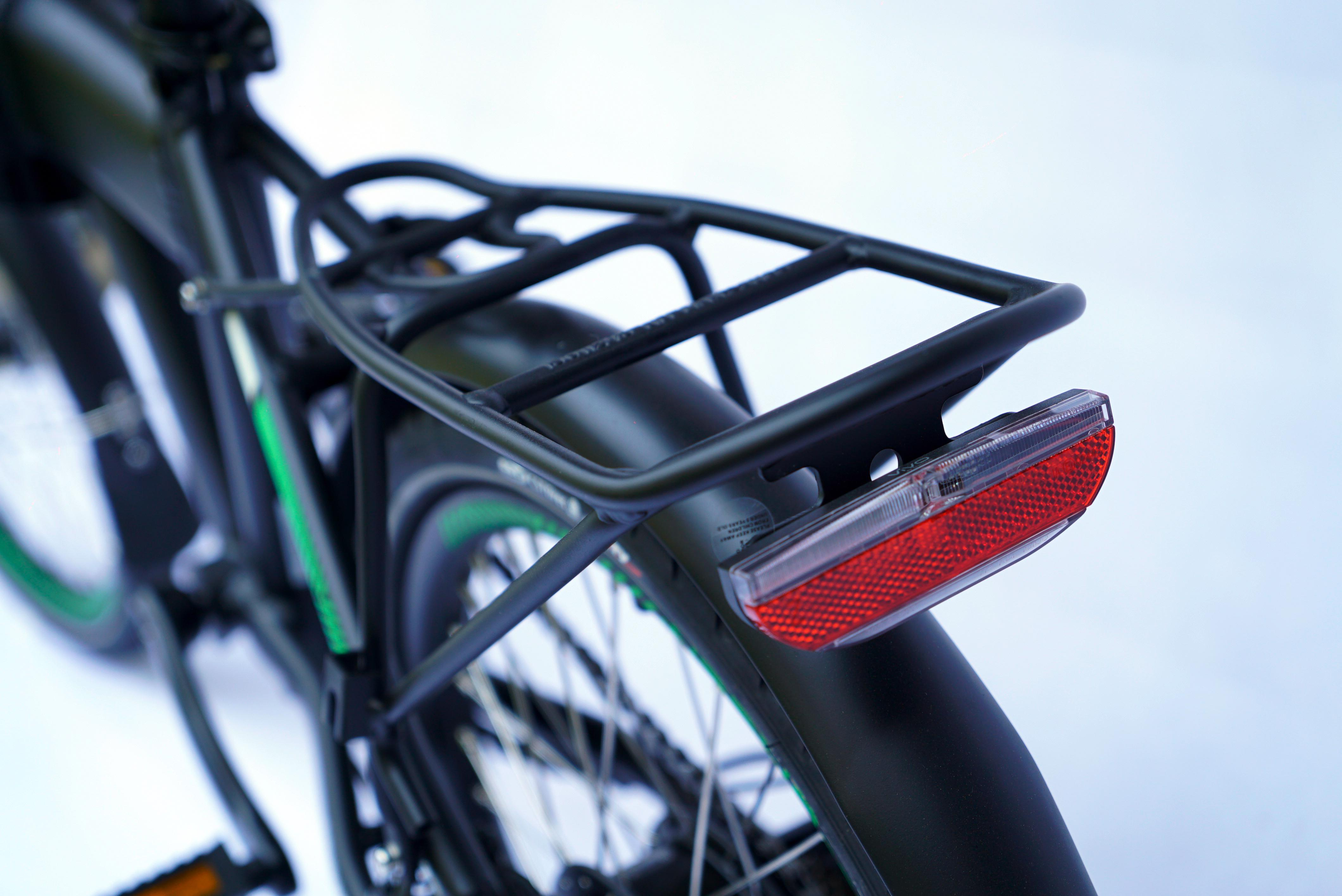 Schwarzes Fahrrad mit Gepäckträger und rotem Reflektor, grüne Akzente auf Rädern vor weißem Hintergrund.
