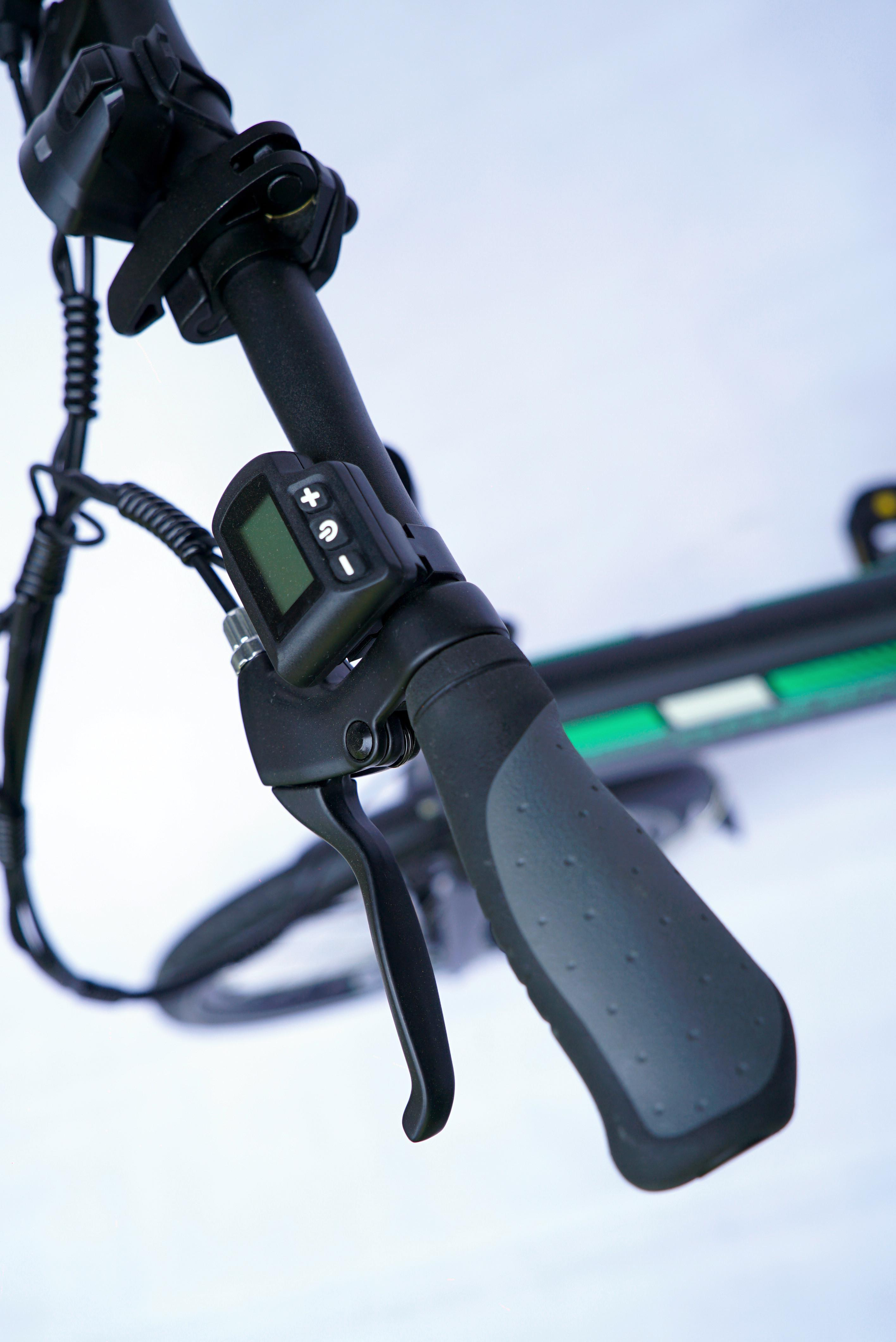 Nahaufnahme des Lenkers eines Elektrorollers mit Bedienelementen und Display.
