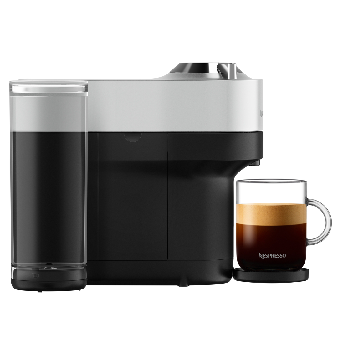 Nespresso-Maschine mit Kaffee. Schwarz-weiße Maschine mit einer Glastasse Kaffee und Wasserbehälter.