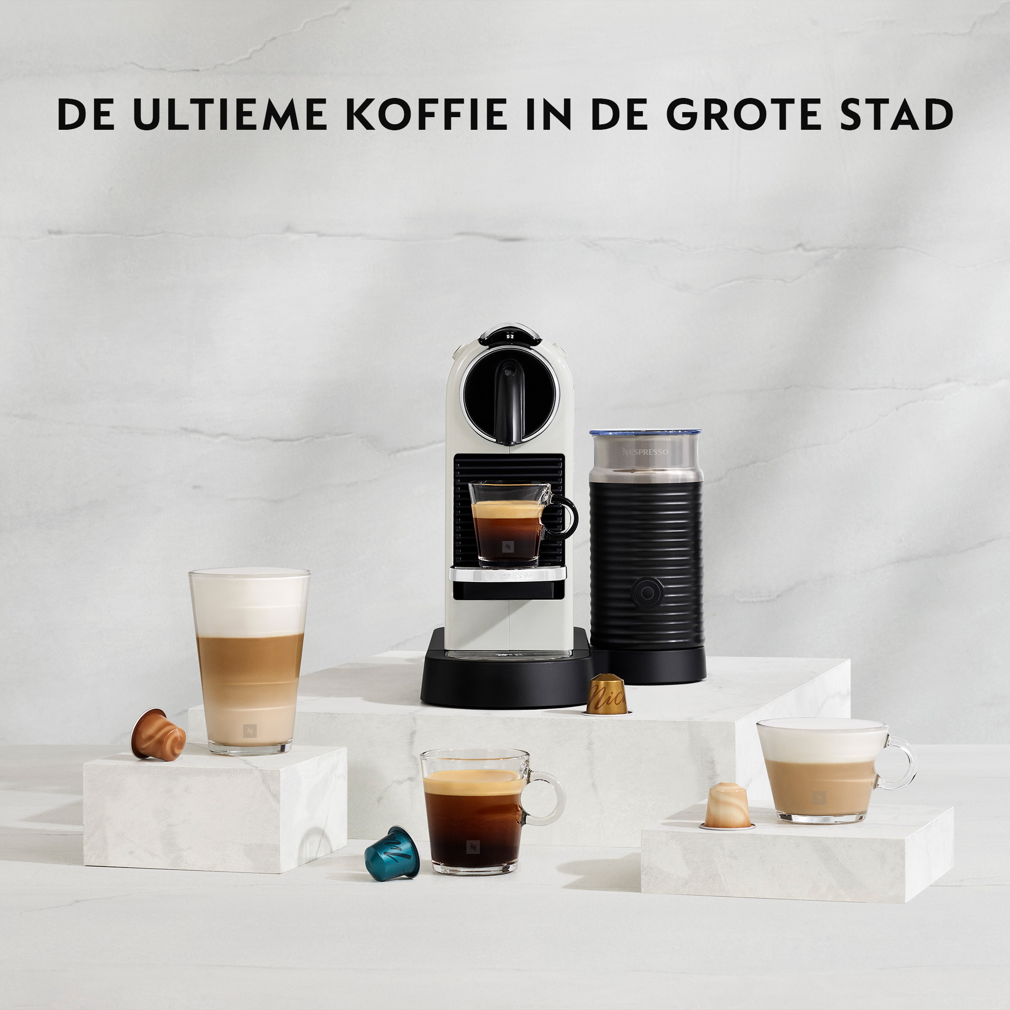 Coffee machine, cups, and capsules on white blocks. Text: The ultimate coffee in the big city.