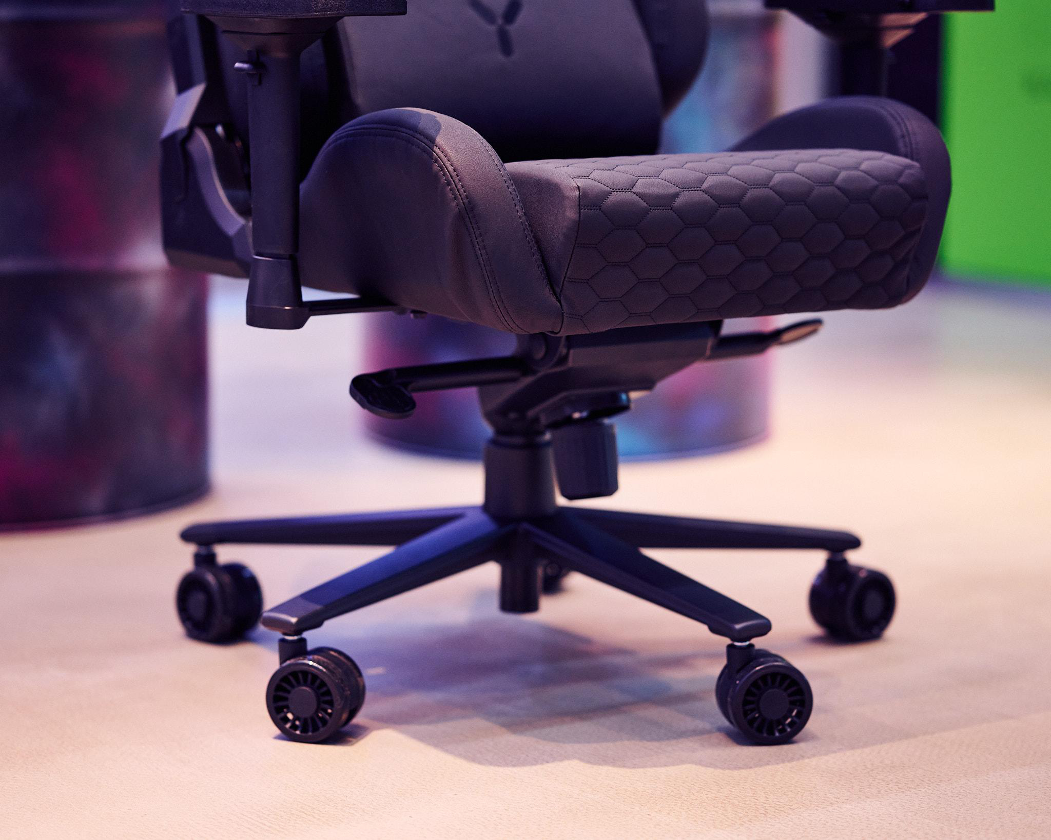 Schwarzer Gaming-Stuhl, schwarzes Gestell, Nahaufnahme der Räder, in einem Raum.