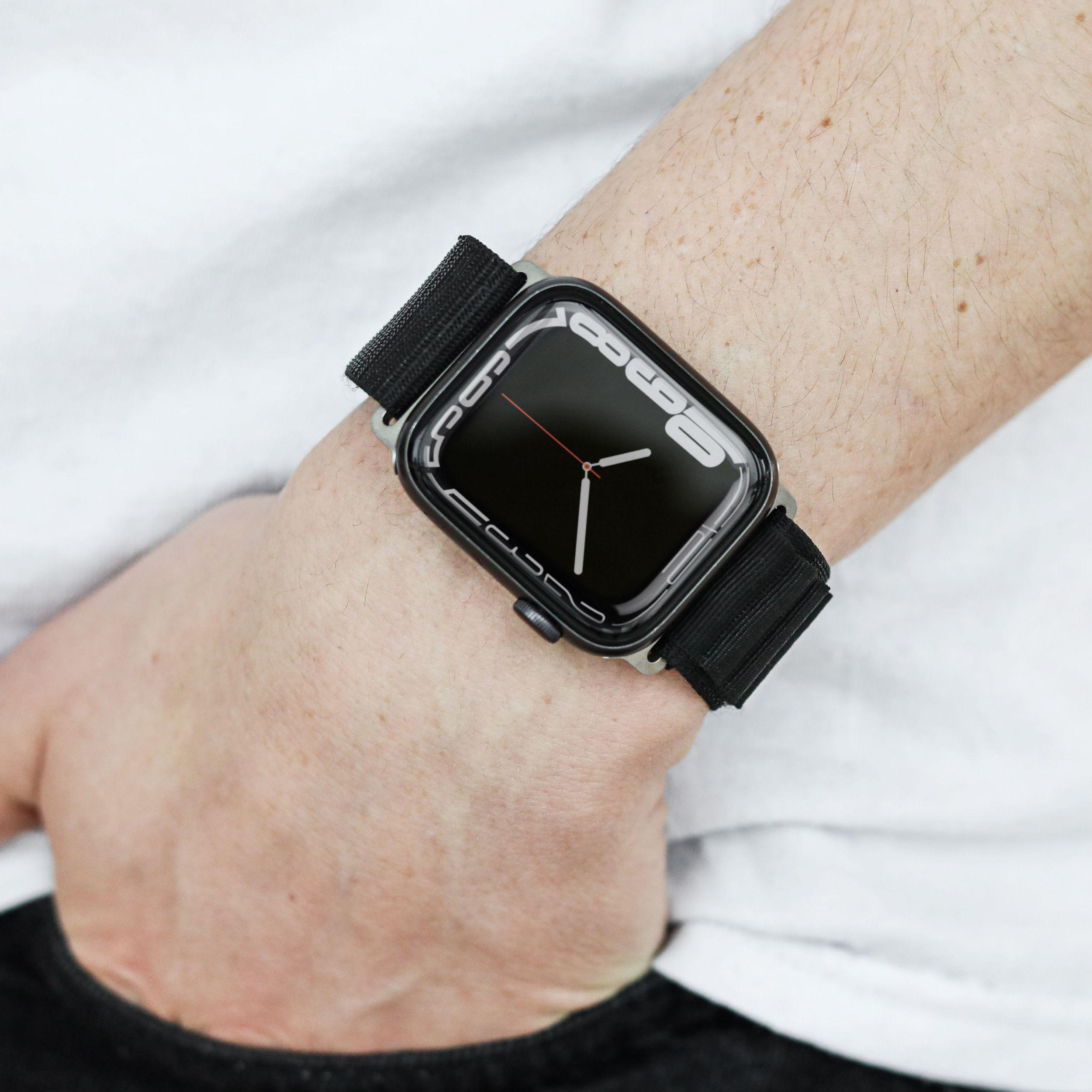 Das Handgelenk einer Person mit einer schwarzen Apple Watch und einem schwarzen Armband.
