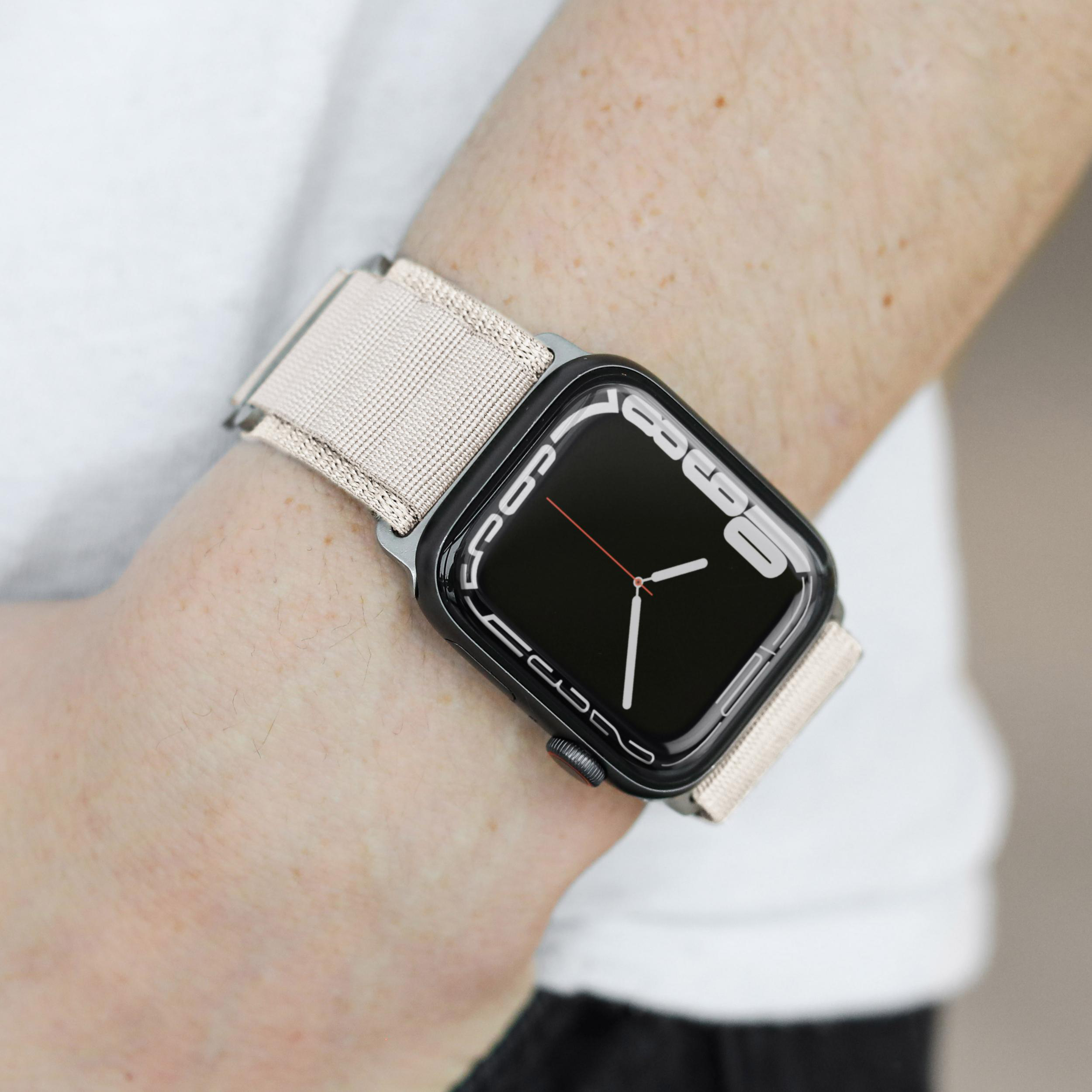 Handgelenk eines Mannes mit Smartwatch und beigem Stoffband.