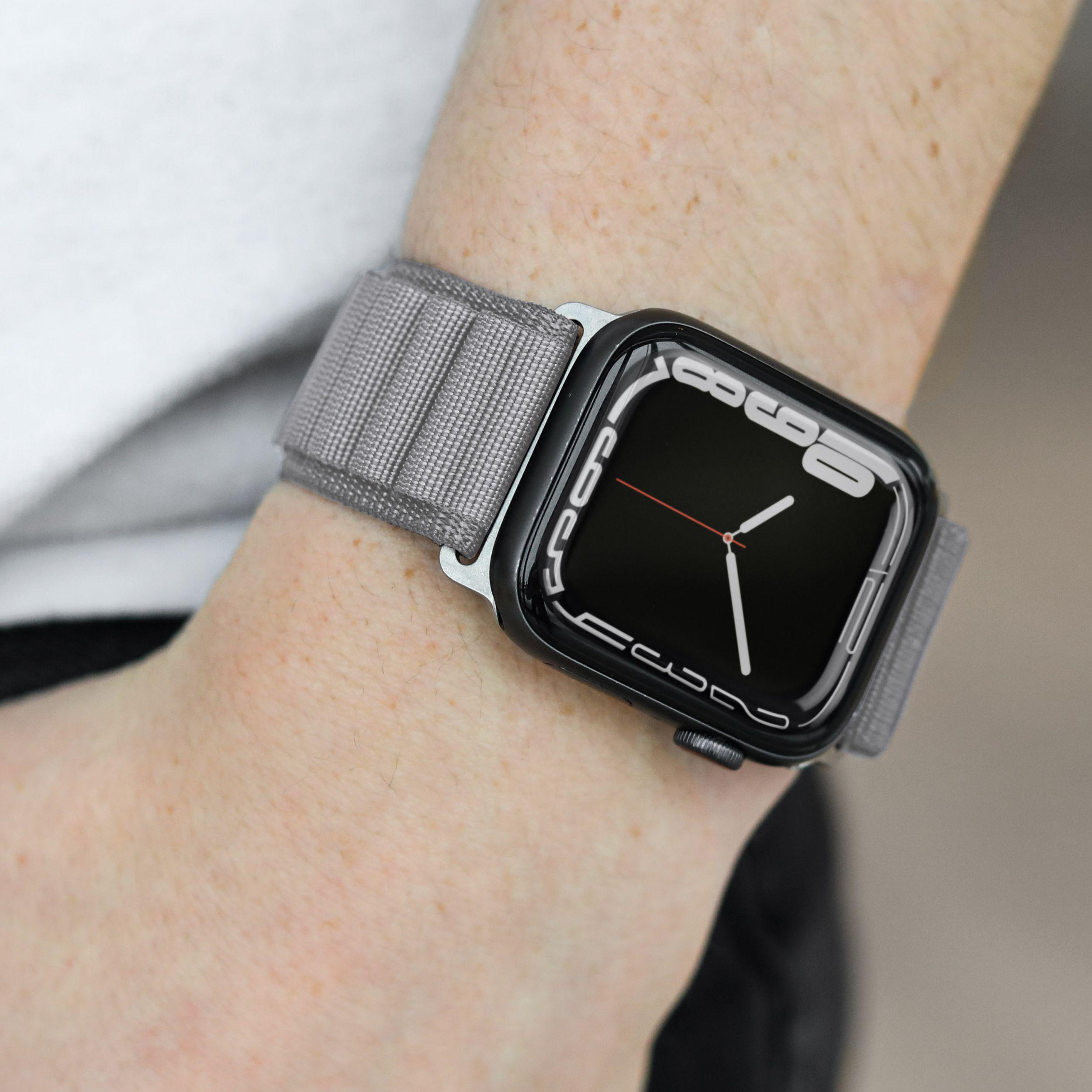 Handgelenk mit Smartwatch, schwarzer Bildschirm, graues Band. Zeigt Uhrzeit und schwarze Lünette, graues Band.