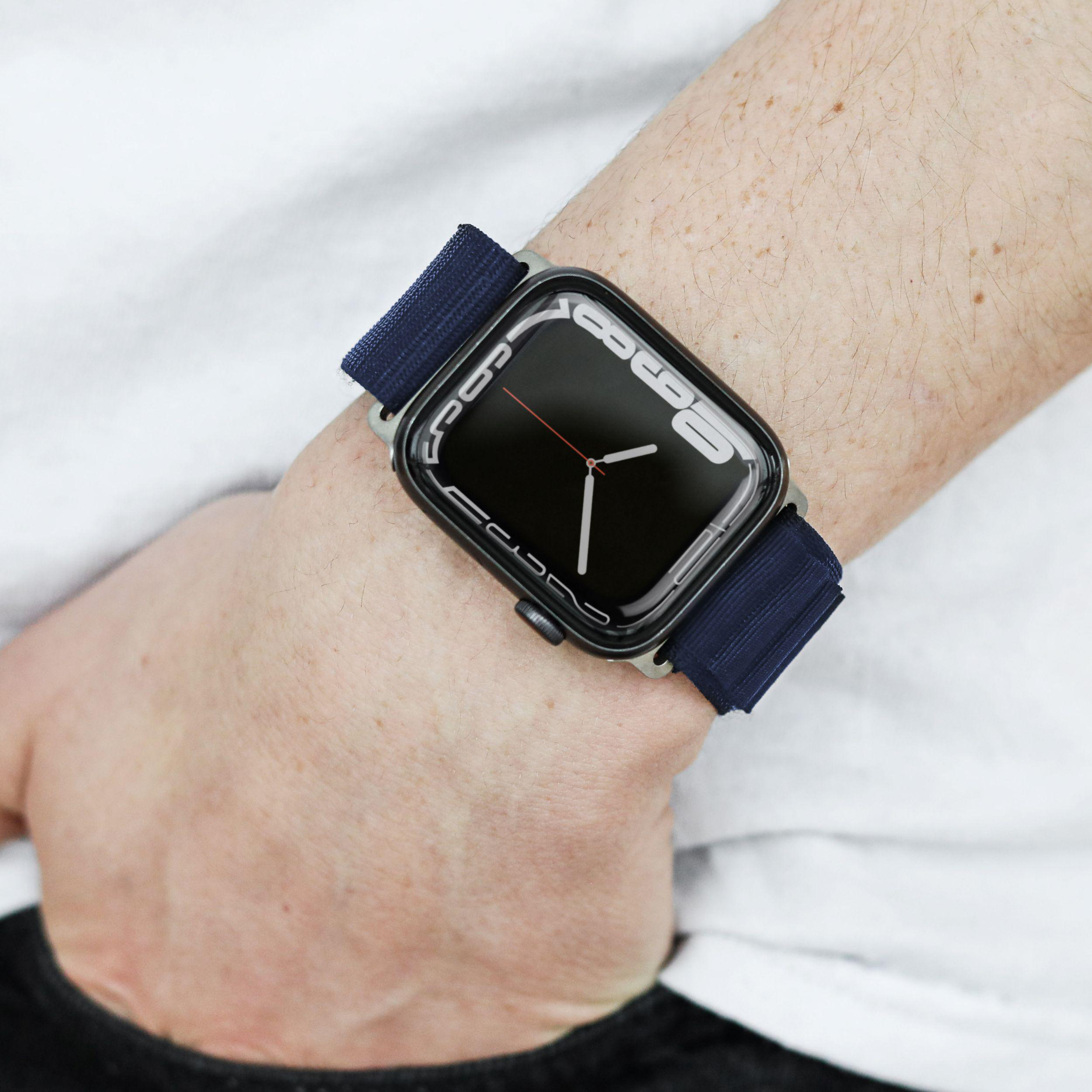 Handgelenk einer Person mit einer schwarzen Smartwatch mit marineblauem Band.