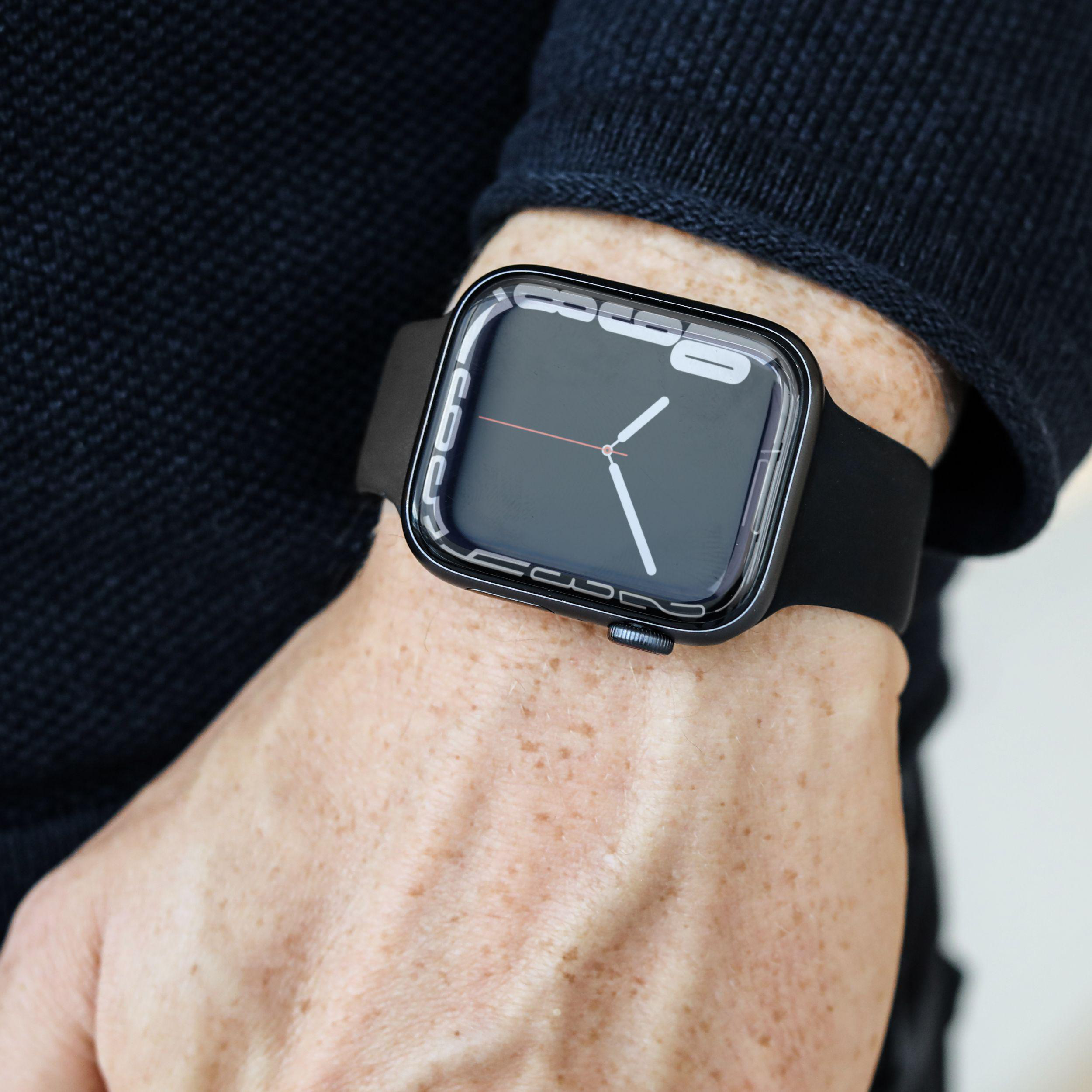 Eine Person trägt eine schwarze Smartwatch mit schwarzem Armband, die die Uhrzeit anzeigt.