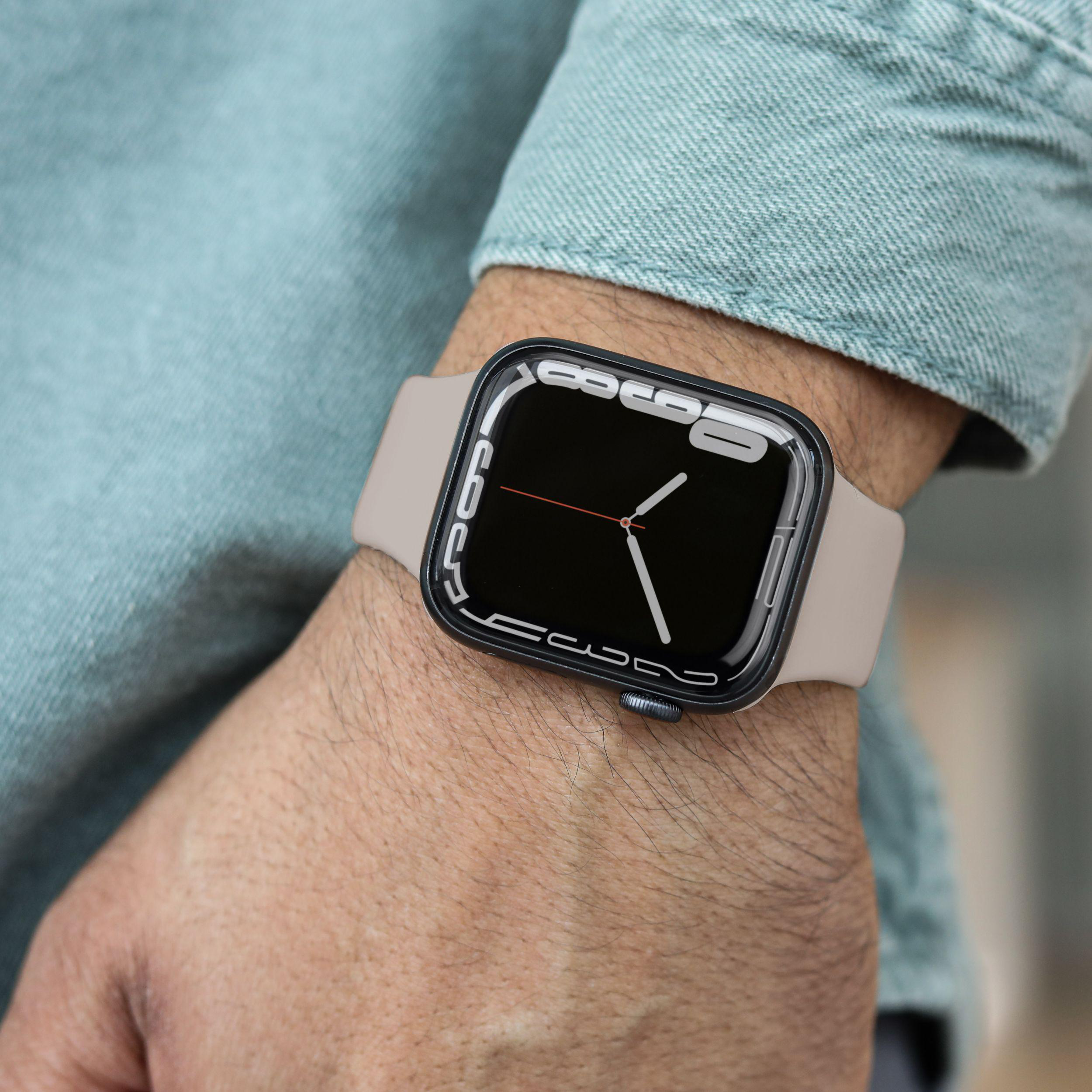Person trägt eine Smartwatch. Die Uhr hat einen schwarzen Bildschirm und ein beiges Armband.