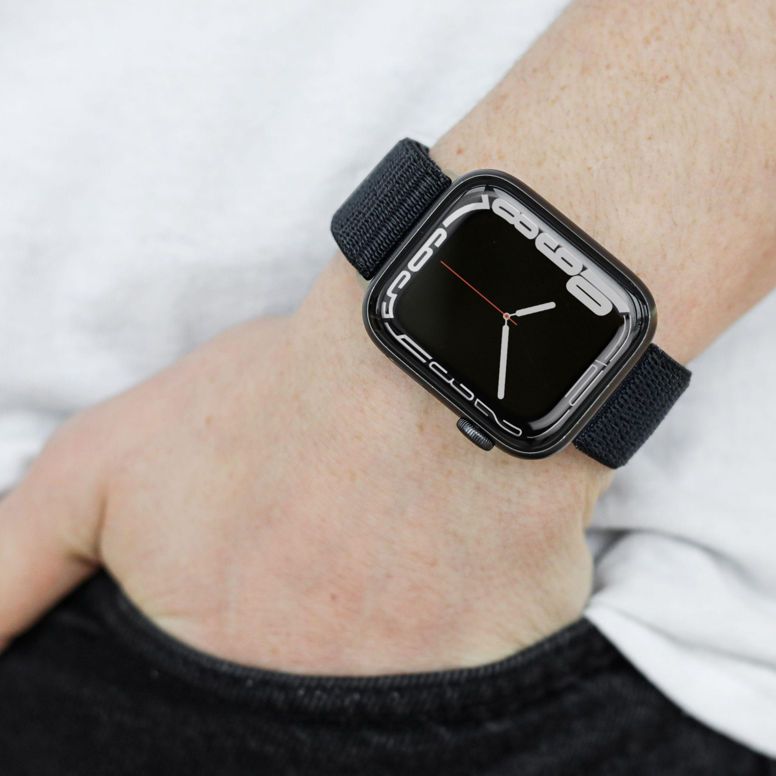 Eine schwarze Smartwatch am Handgelenk, zeigt eine digitale Oberfläche mit Zeit.