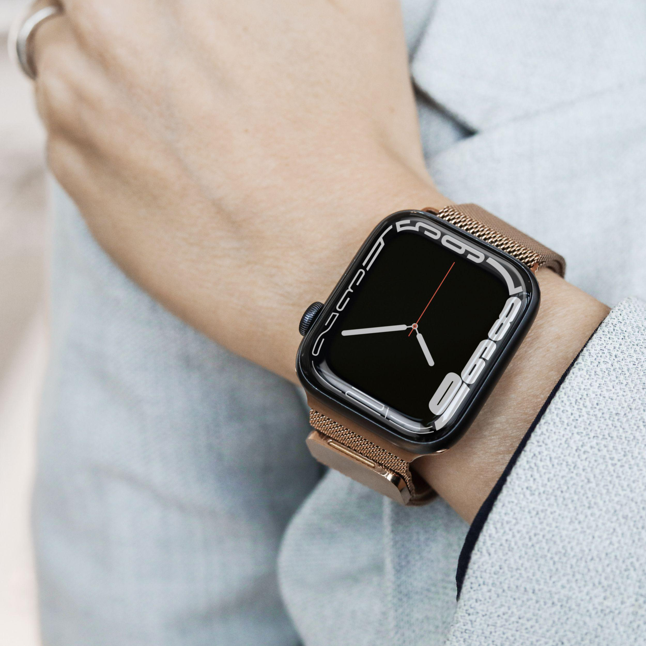 Das Handgelenk einer Person mit einer Smartwatch wird gezeigt. Die Uhr ist schwarz und hat ein Metallarmband.