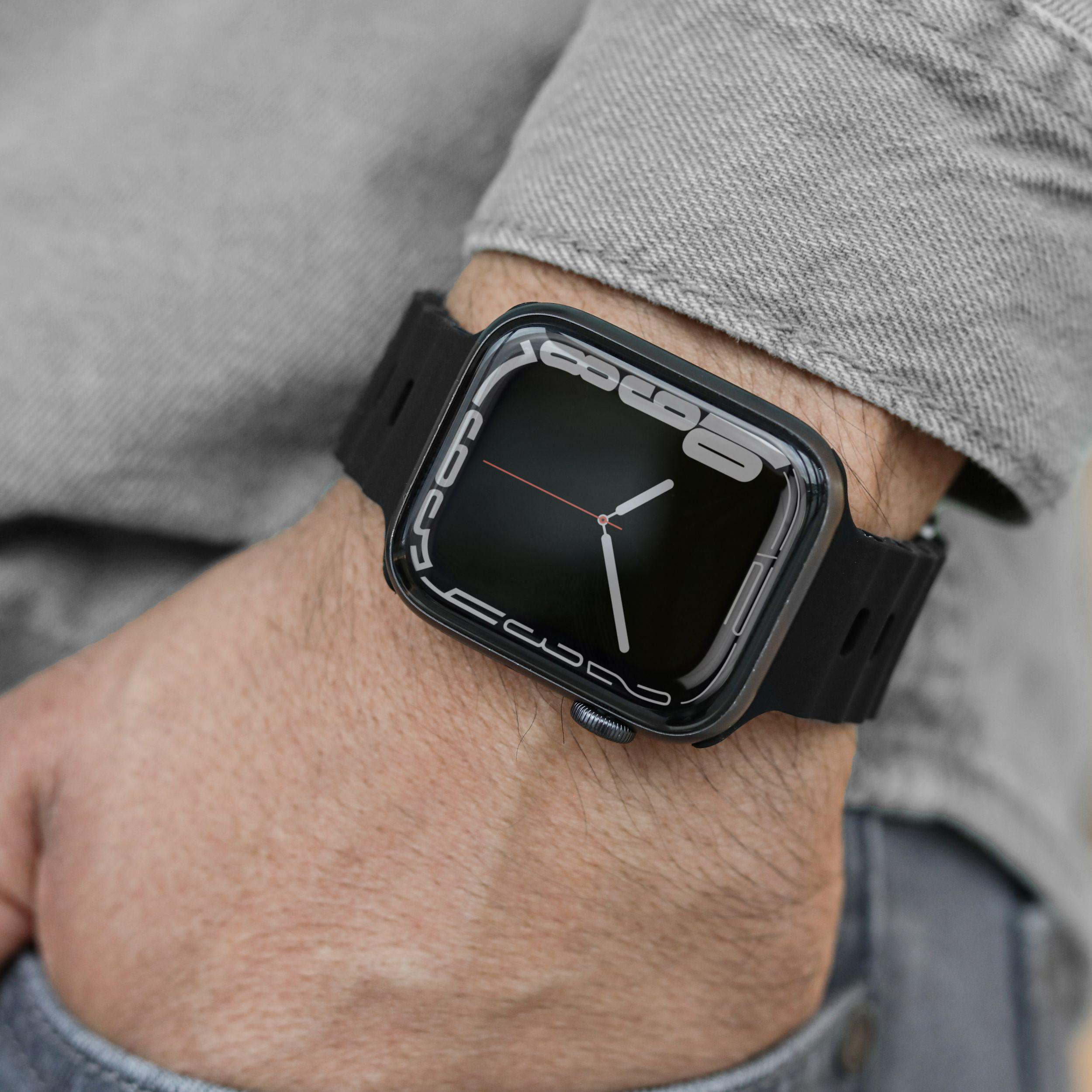 Schwarze Apple Watch am Handgelenk. Das Display ist schwarz. Die Uhr ist auf einem grauen Hemd.