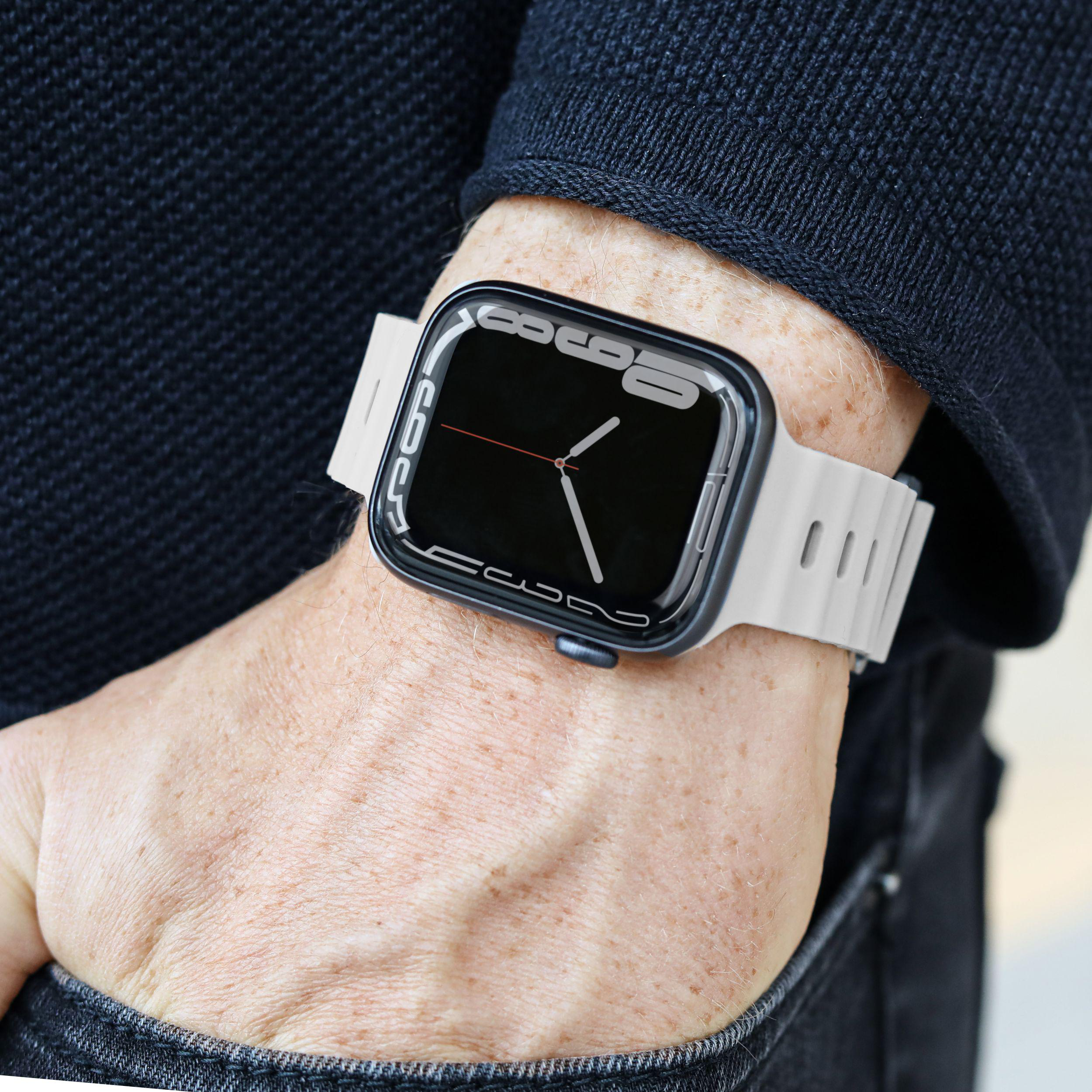 Eine Person trägt eine Uhr am Handgelenk. Die Uhr hat ein weißes Armband und ein schwarzes Zifferblatt.