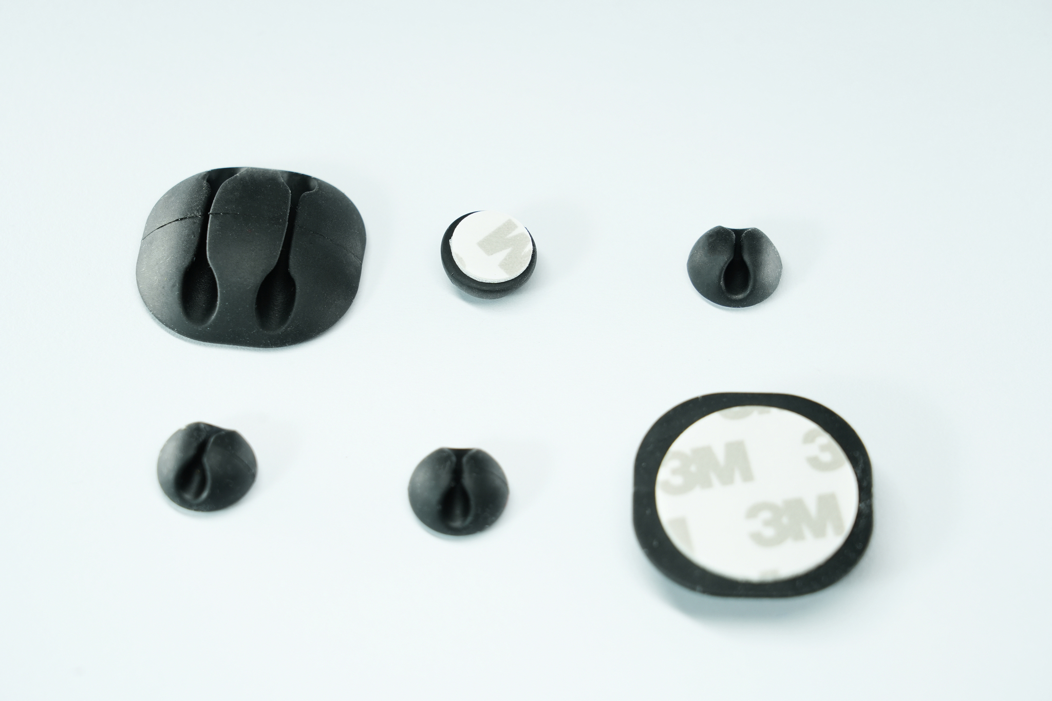 Organisateurs de câbles noirs. Cinq organiseurs de différentes formes et tailles sur une surface blanche.