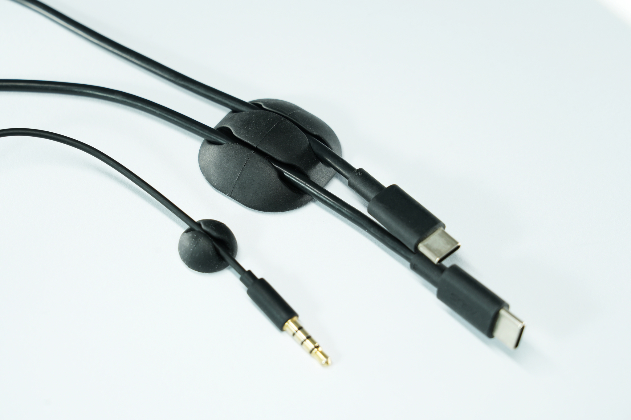 Câbles noirs avec organiseurs. Un câble a une prise jack 3,5 mm, d'autres des connecteurs USB-C.