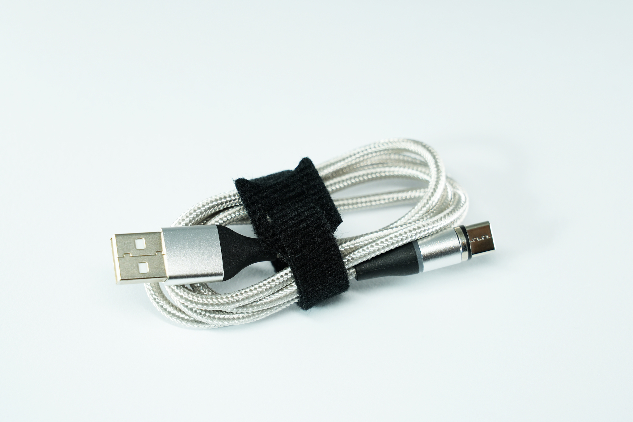 Un câble de chargement USB enroulé et fixé avec une sangle velcro noire.