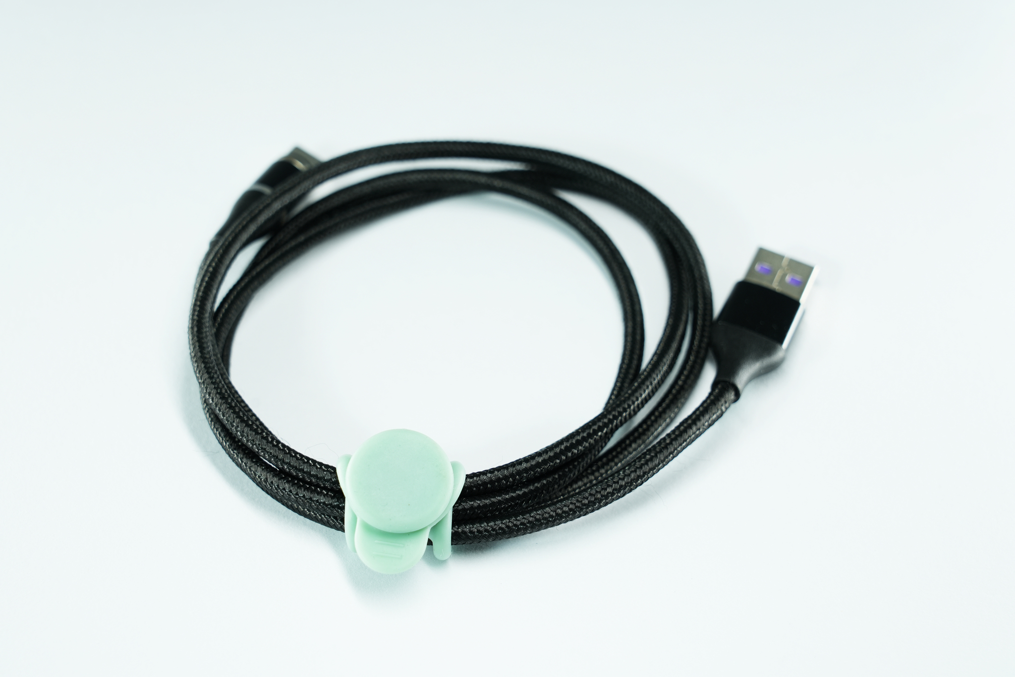 Cavo USB nero con supporto verde. È su uno sfondo bianco.