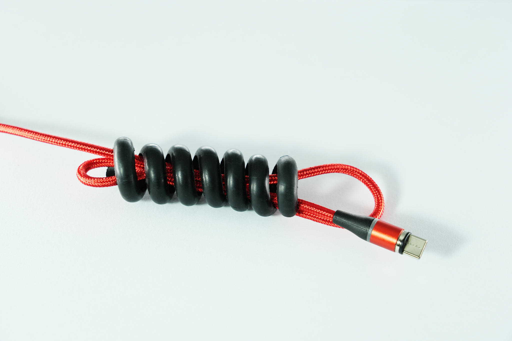 Câble rouge tressé avec des anneaux en caoutchouc noirs. Connecteur USB-C à l'extrémité.