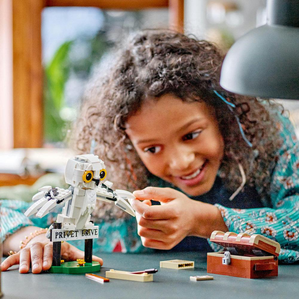 Mädchen baut eine Lego-Eule. Text: Privet Drive Schild.