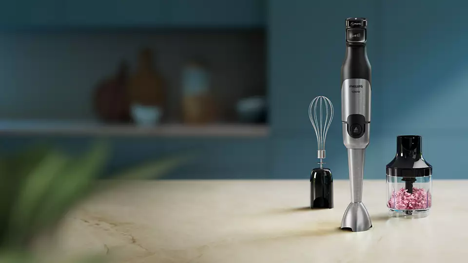 Kézi mixer tartozékokkal a pulton. Habverőt és aprítót tartalmaz, homályos háttérrel.