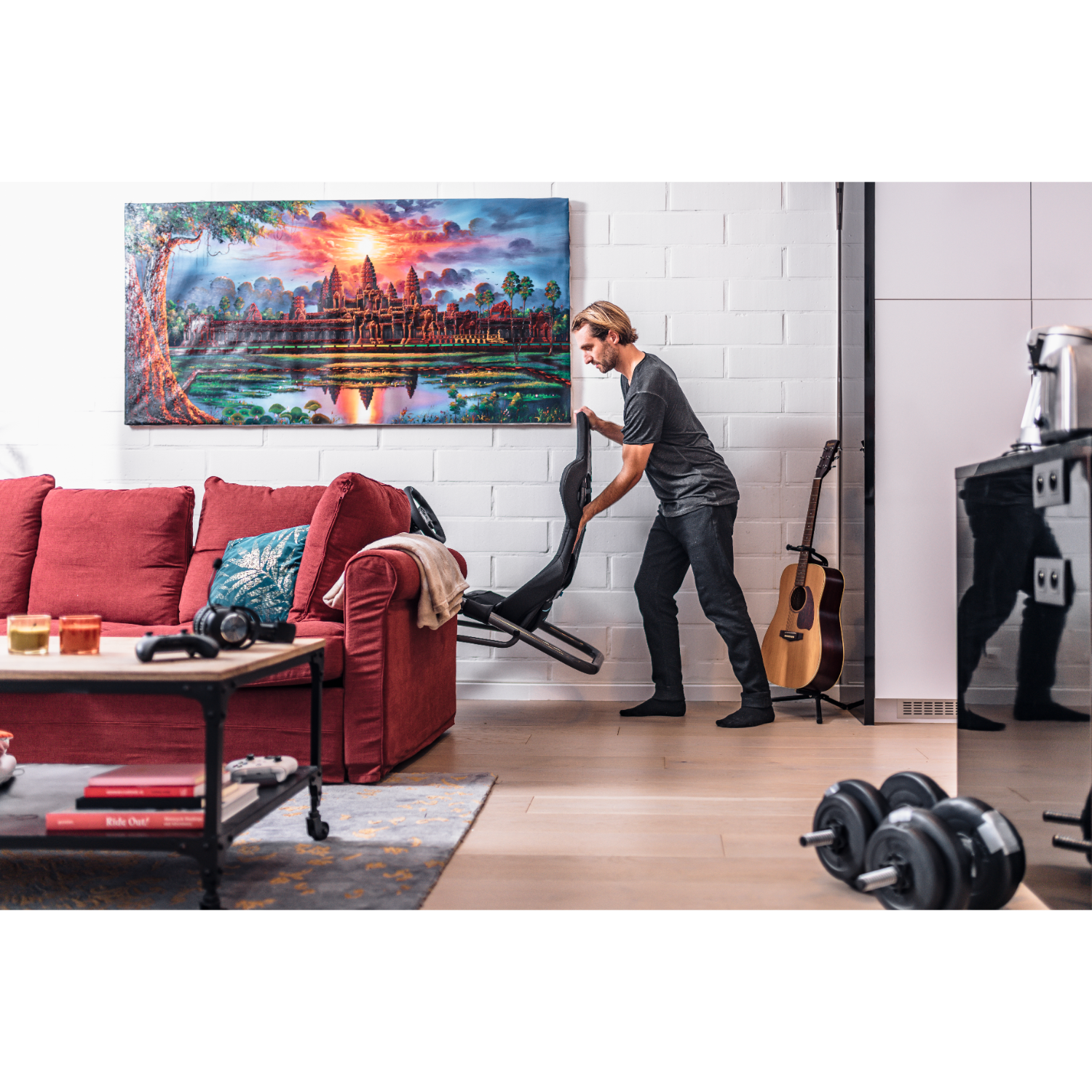 Man die een gitaar in zijn koffer pakt in een woonkamer met een rode bank.