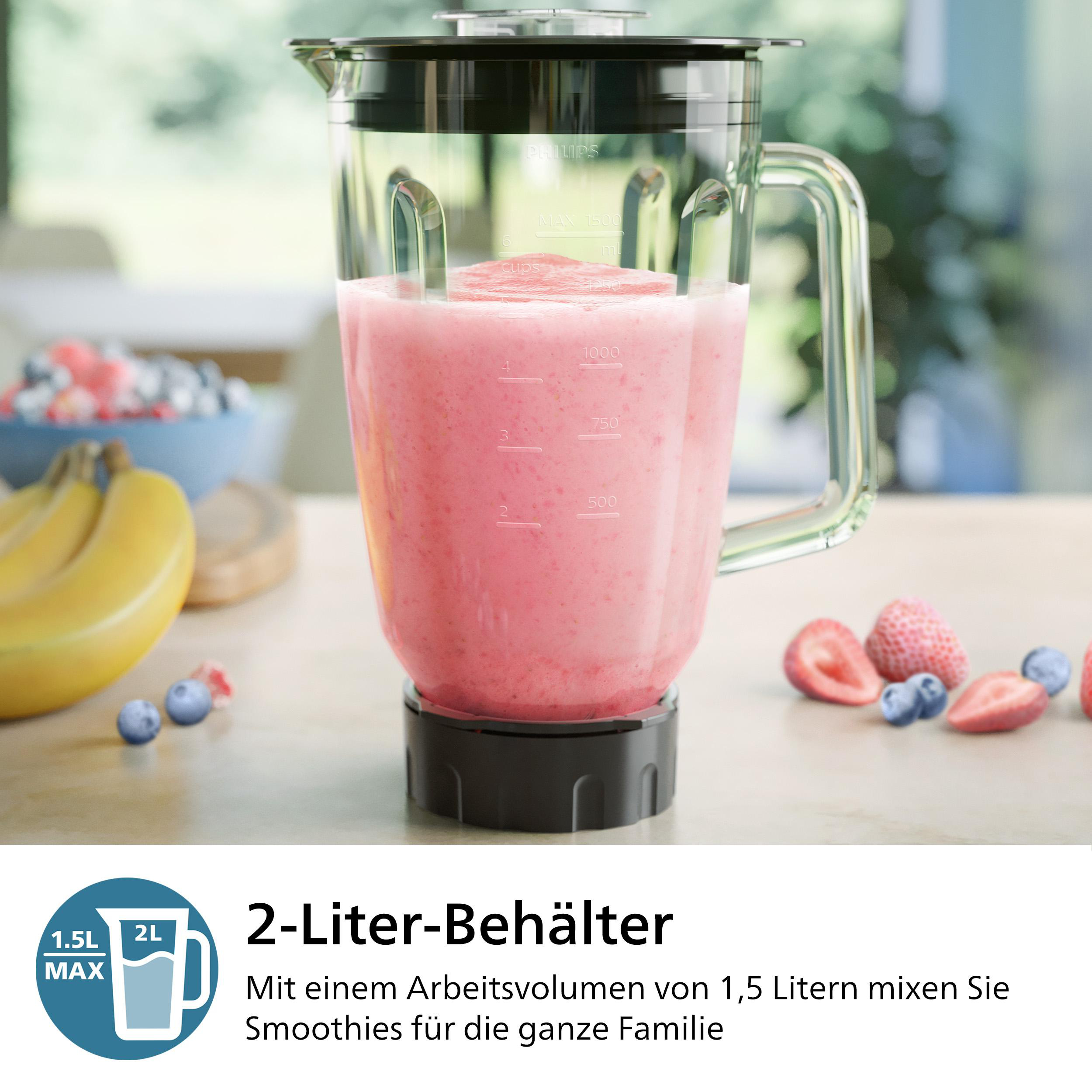Mixer mit pinkfarbenem Smoothie, Blaubeeren, Erdbeeren und Bananen auf hellem Holztisch.