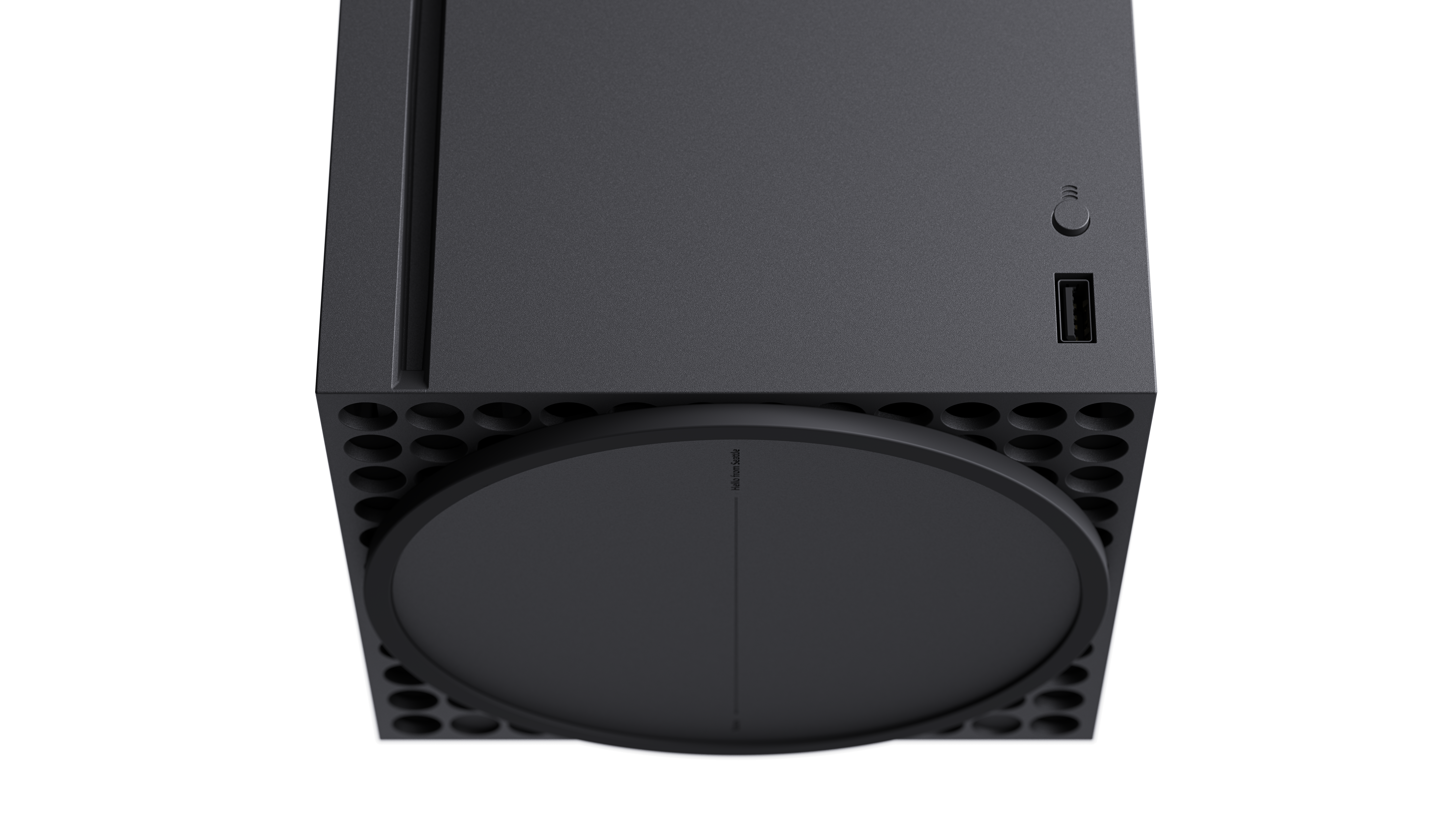 Vista superior de una Xbox Series X negra. Tiene el botón de encendido y el puerto USB visibles. Diseño de base redondeada.