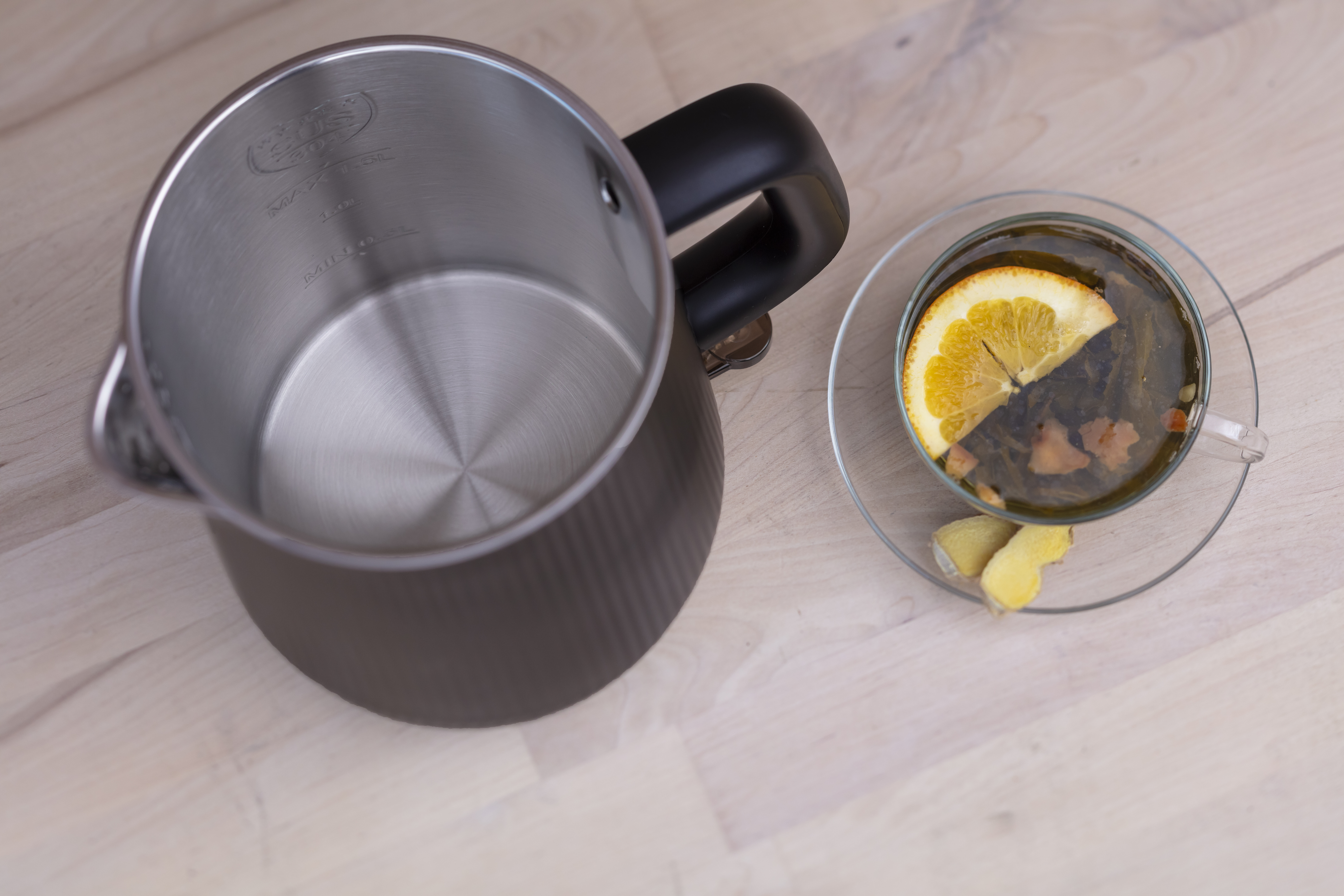 Czajnik z filiżanką herbaty, plaster pomarańczy, imbir, drewniana powierzchnia, z góry.