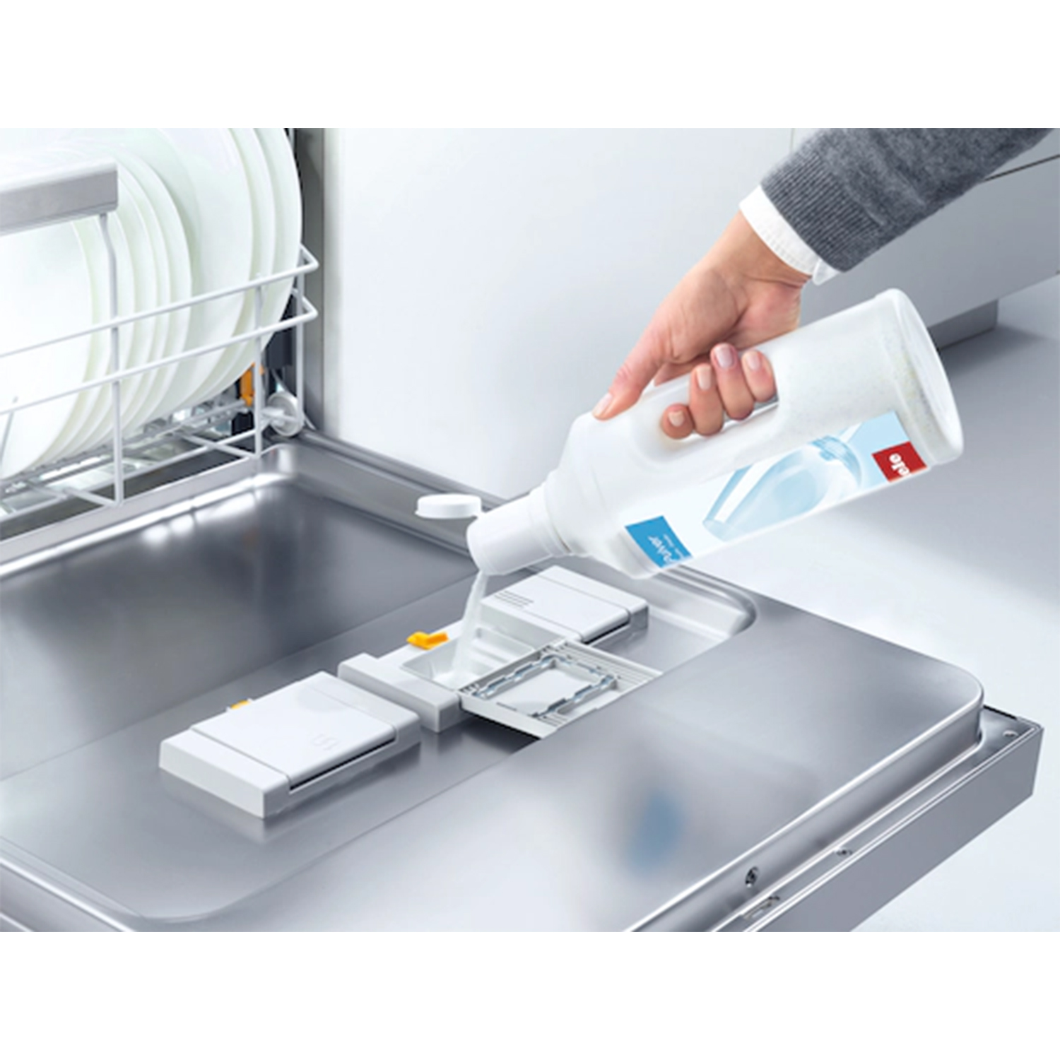 Una persona versa detersivo per lavastoviglie nel dispenser.
