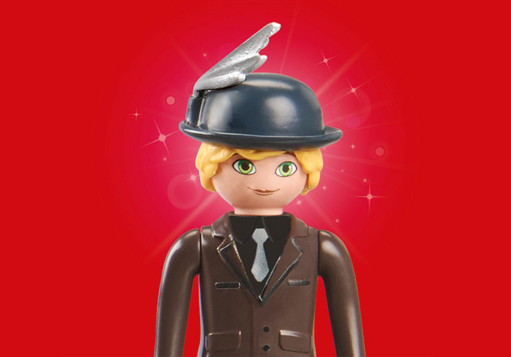 Eine Playmobil-Figur eines Mannes in einem braunen Anzug und einem schwarzen Hut mit einem silbernen Flügel auf rotem Hintergrund.
