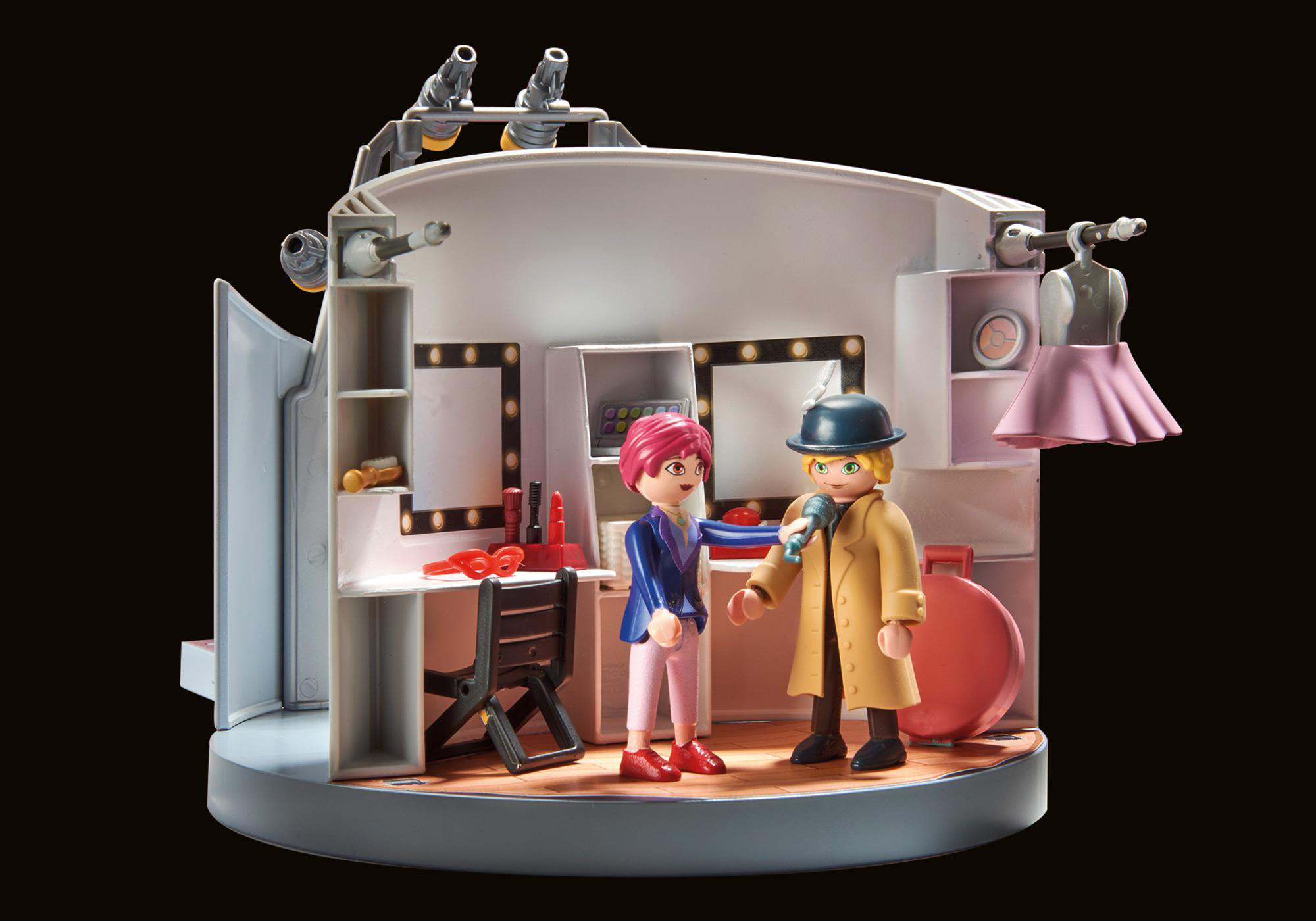 Eine Bühnenszene mit zwei Figuren. Einer mit Hut und Mikrofon, der andere gestikuliert.