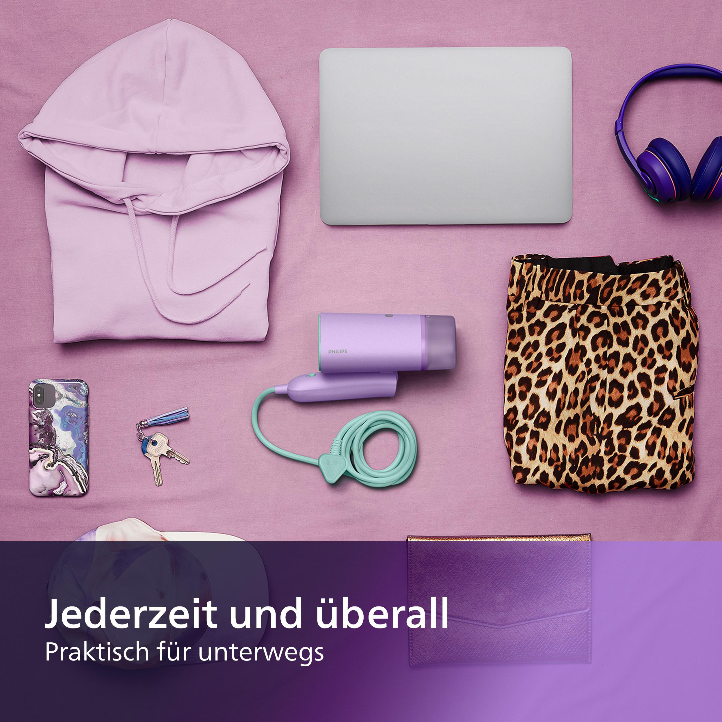 Ein Flatlay von Gegenständen, darunter ein Haartrockner, Laptop und Zubehör.