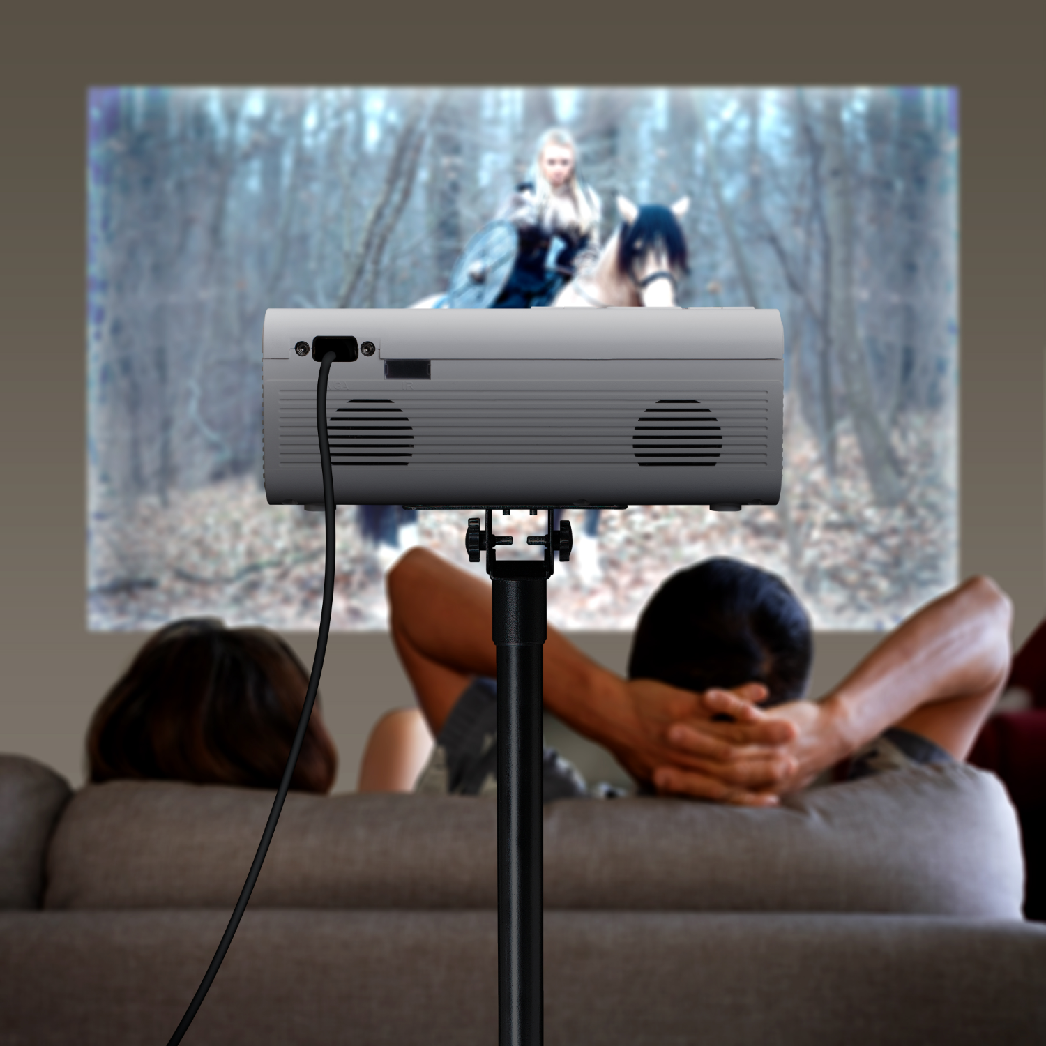 Projecteur sur pied projetant un film sur un mur. Deux personnes en arrière-plan.