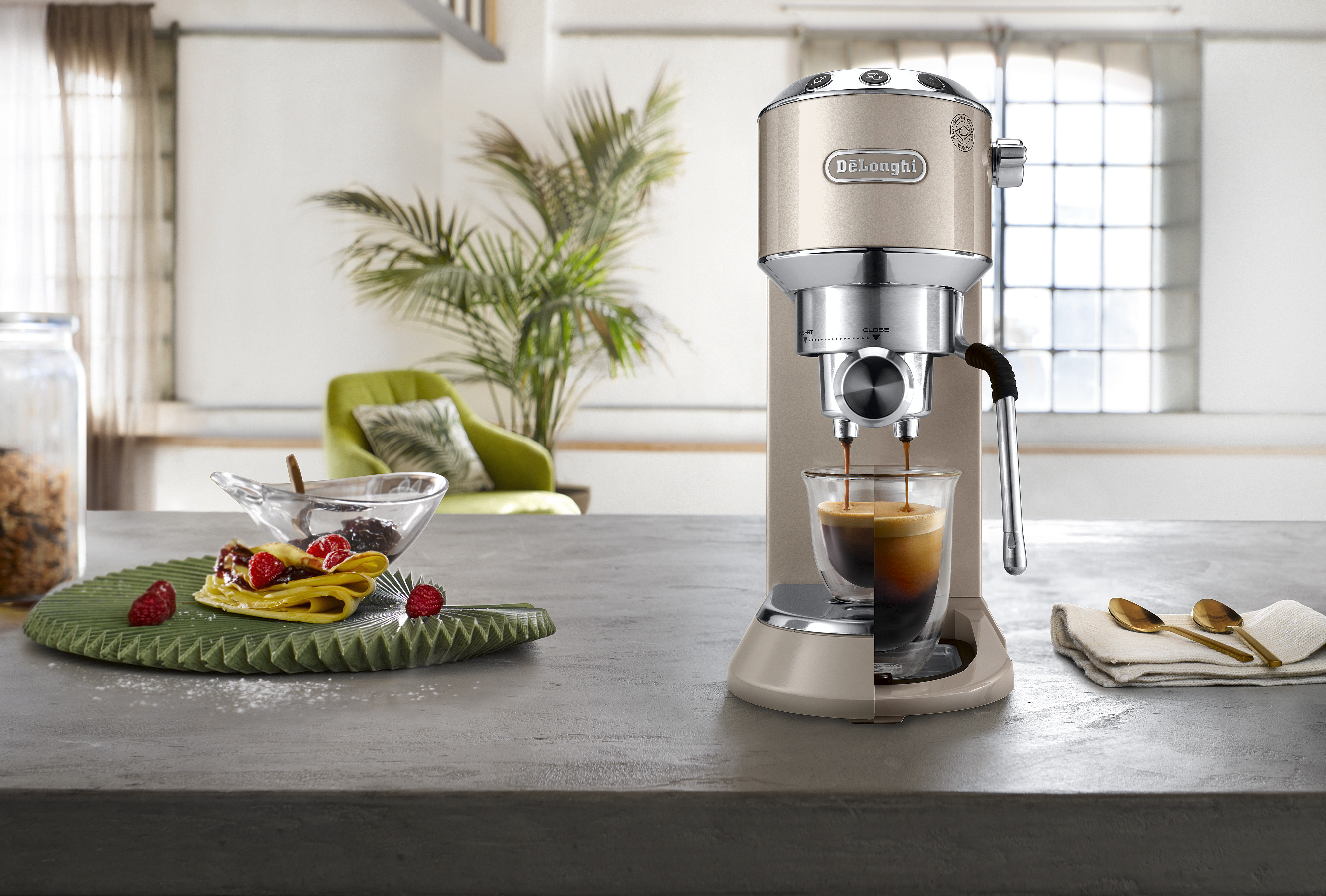 Ekspres do kawy robiący kawę. Kawa wlewa się do szklanki. Beżowa maszyna, metaliczne akcenty. Zielona taca.