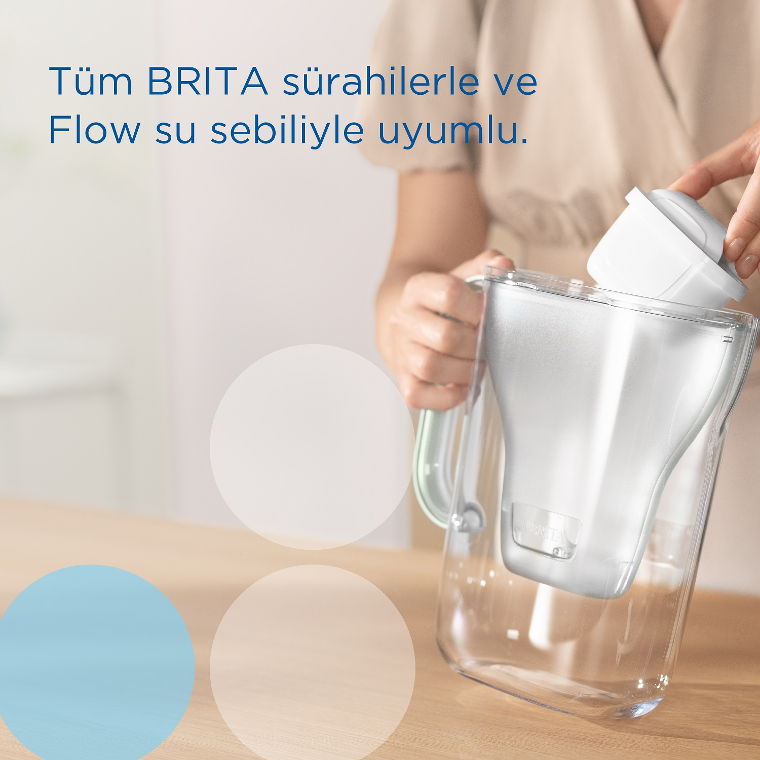 Bir kişi, şeffaf bir su sürahisine beyaz bir filtre ekliyor.