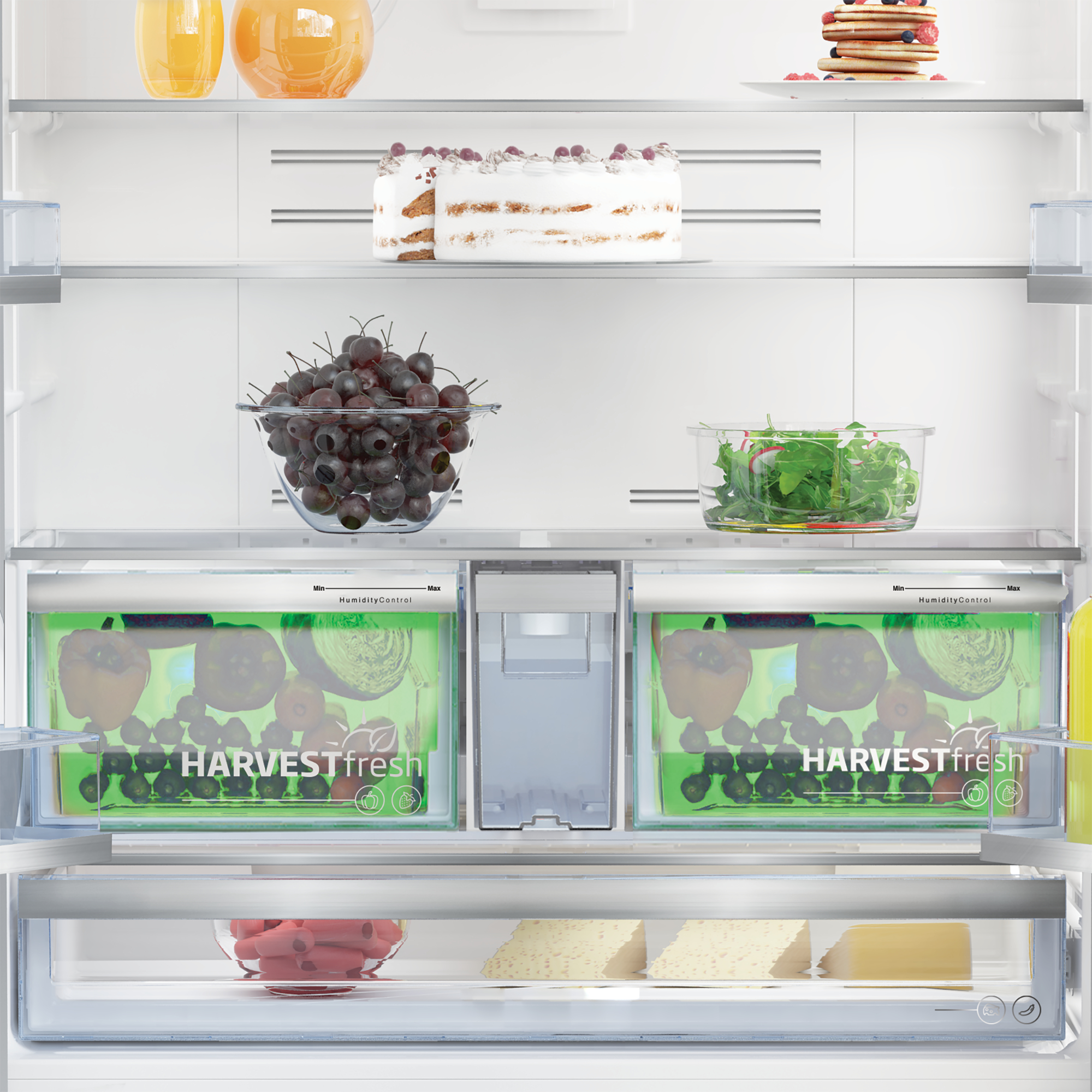 Wnętrze lodówki z jedzeniem: winogrona, sałata, ciasto, jagody. Widoczne szuflady Harvest Fresh.
