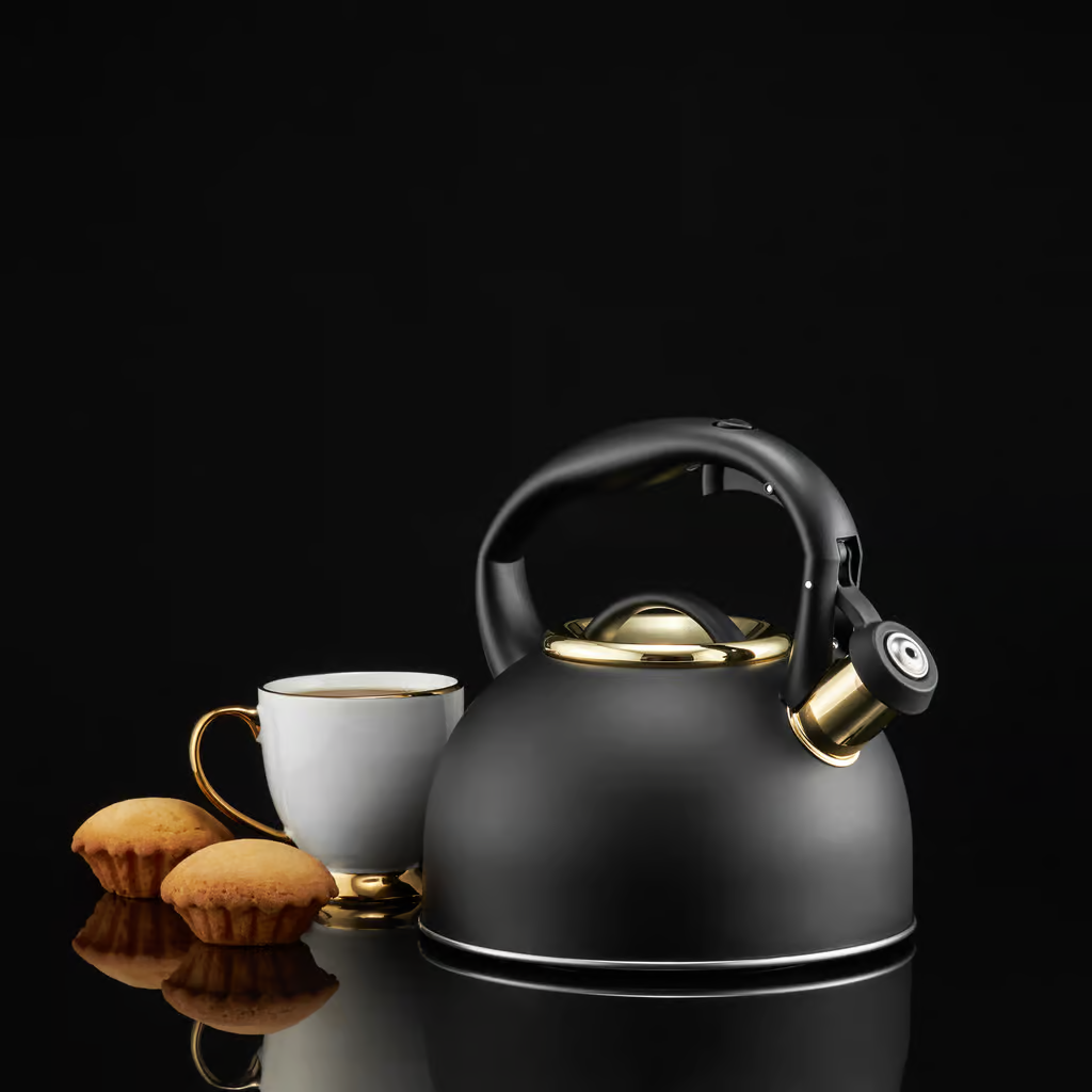 Czarny czajnik ze złotymi akcentami, biała filiżanka ze złotym rantem, babeczki, na odblaskowej powierzchni.
