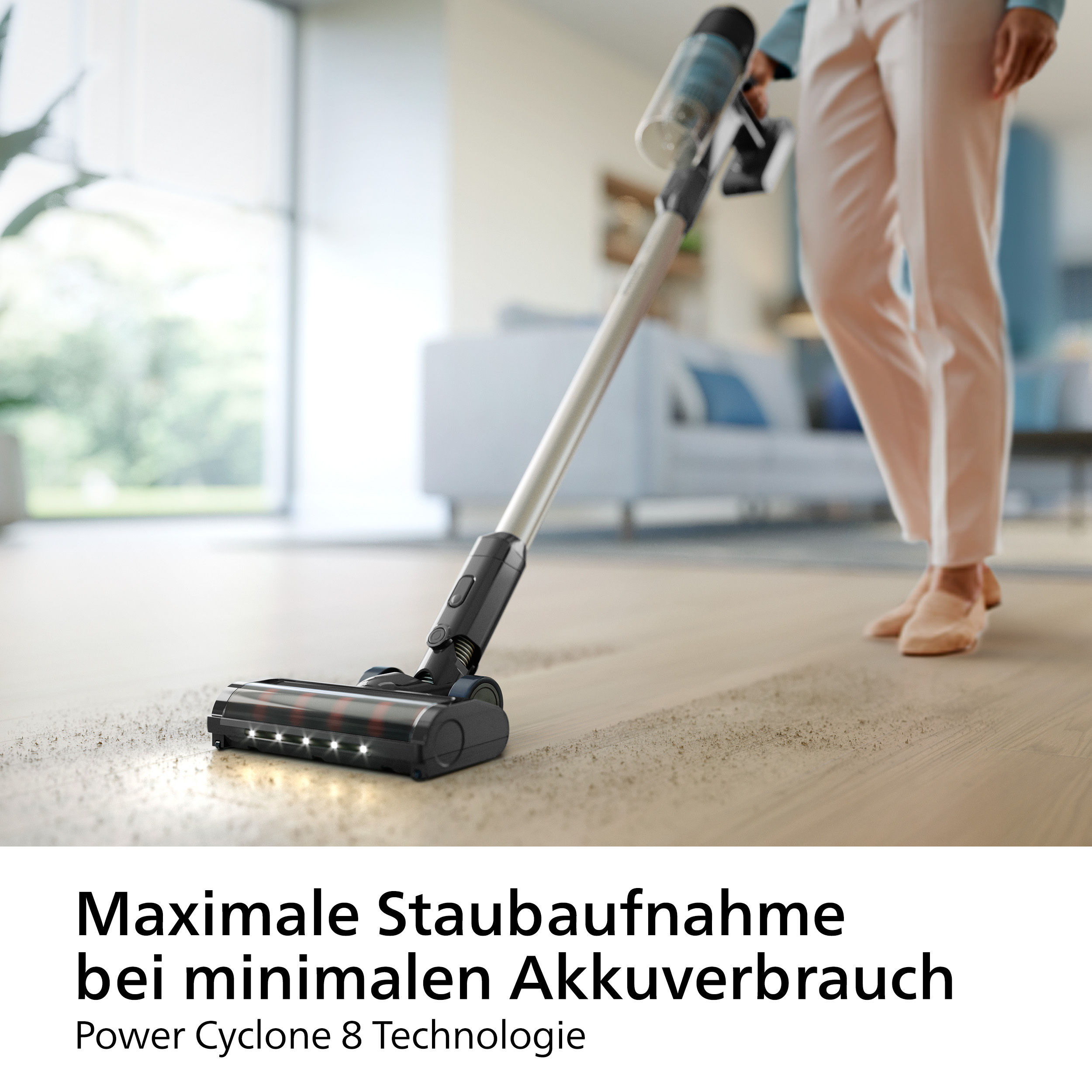 Eine Person saugt einen Holzboden mit einem kabellosen Staubsauger ab.