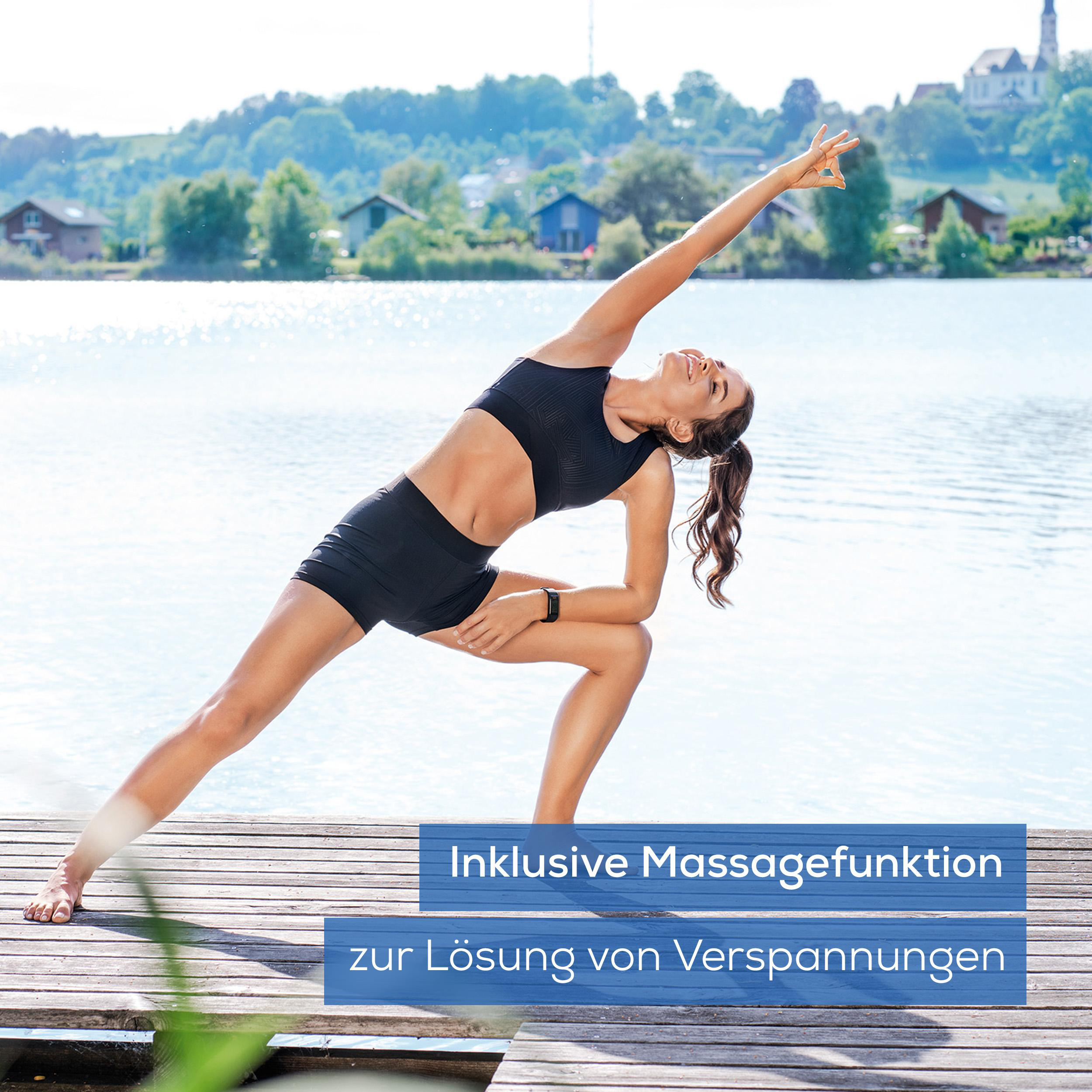 Eine Frau macht Yoga auf einem Holzsteg am See. Text auf Deutsch über Massagefunktion ist vorhanden.